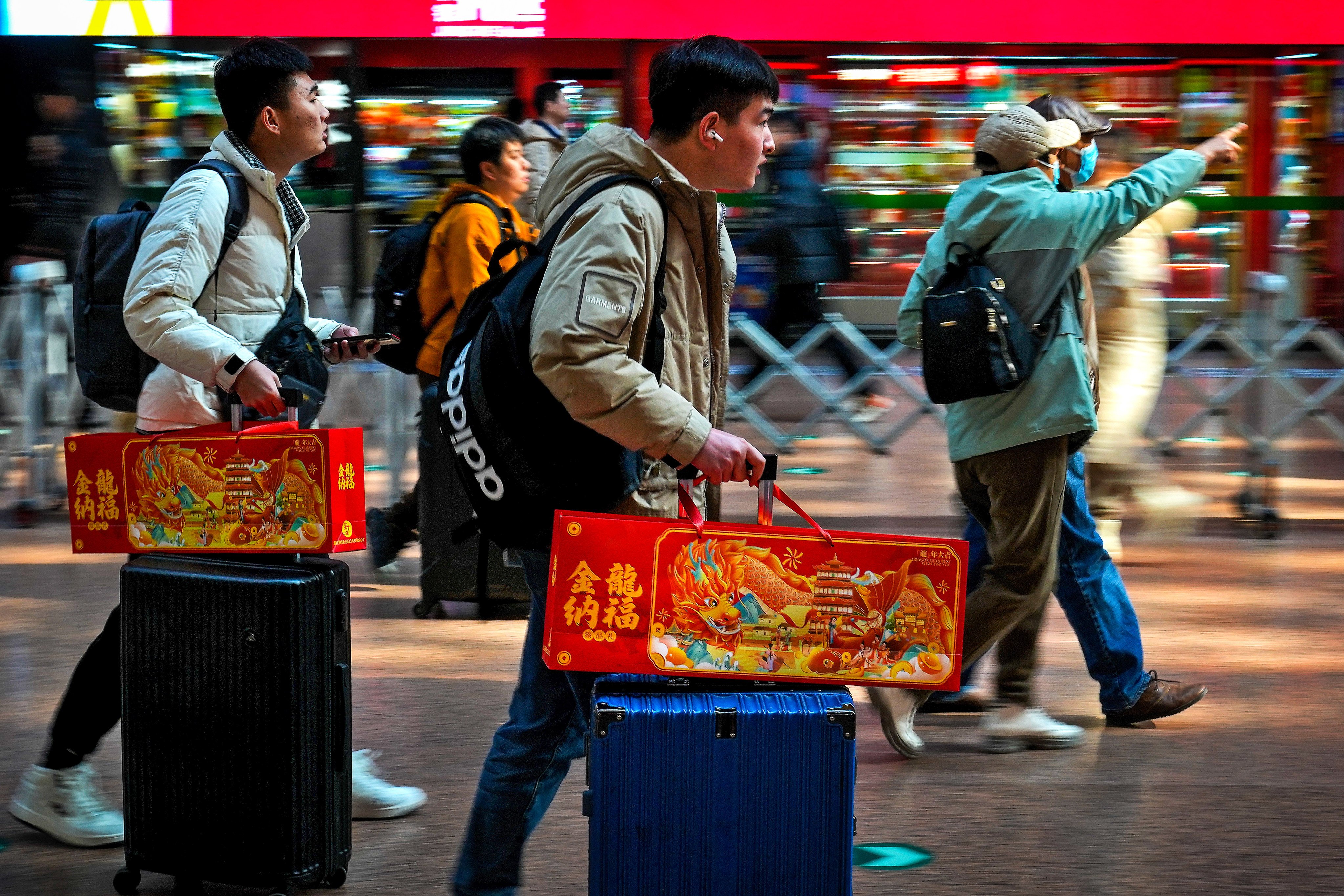Travelers with their luggage and Lunar New Year goodies arrive at a departure hall to catch trains at the West Railway Station in Beijing on Saturday. Authorities expected this year’s Lunar New Year travel surge to be the biggest in years. Photo: AP