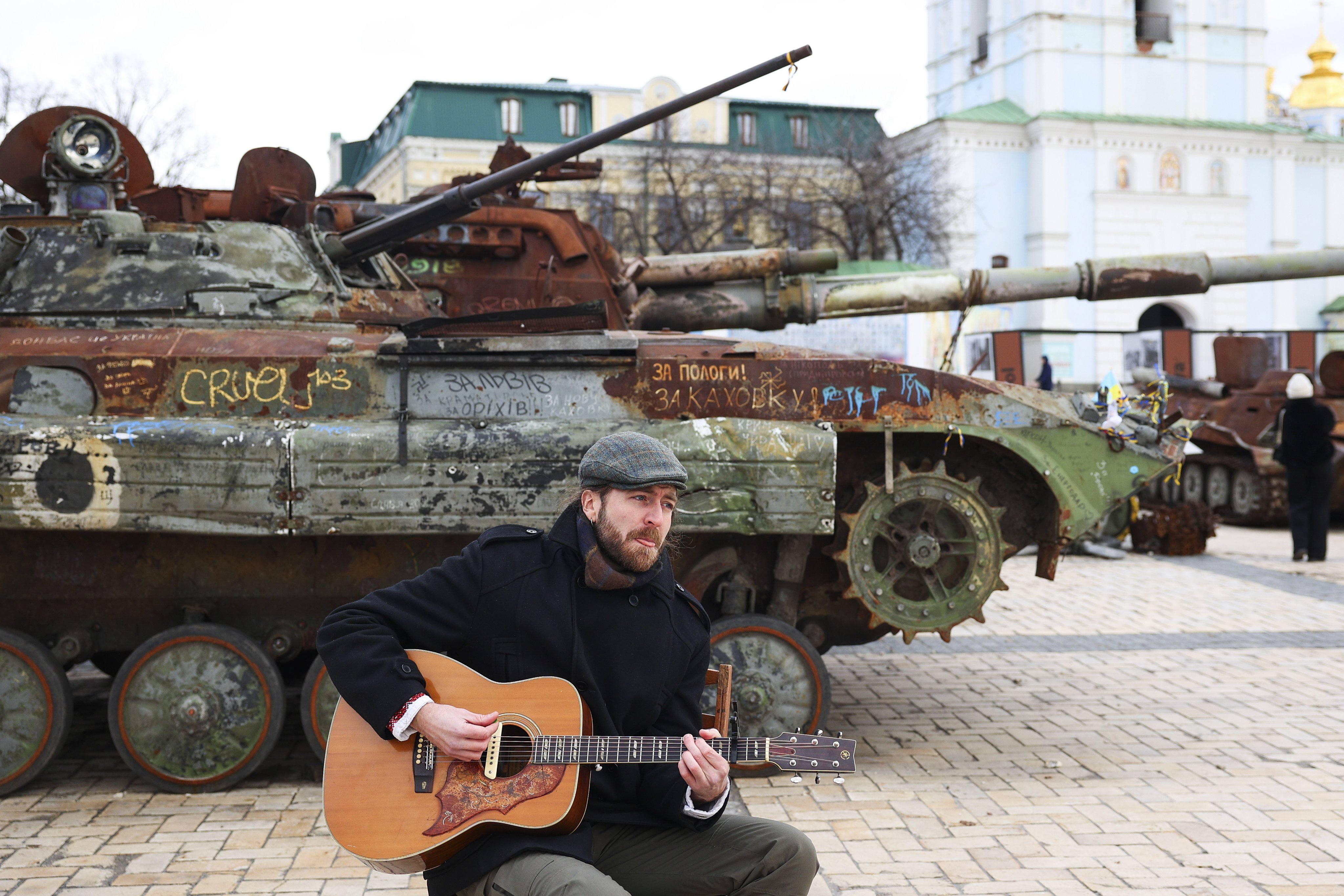 A musician plays the guitar near Russian combat cars, destroyed by the Ukrainian army, that are on display at Mykhailivska Square, in Kyiv, Ukraine, on February 4. Nato believes that Ukraine must prevail as a sovereign independent nation and that Russia must be made to realise that the cost of trying to control Ukraine is too high. Photo: EPA-EFE