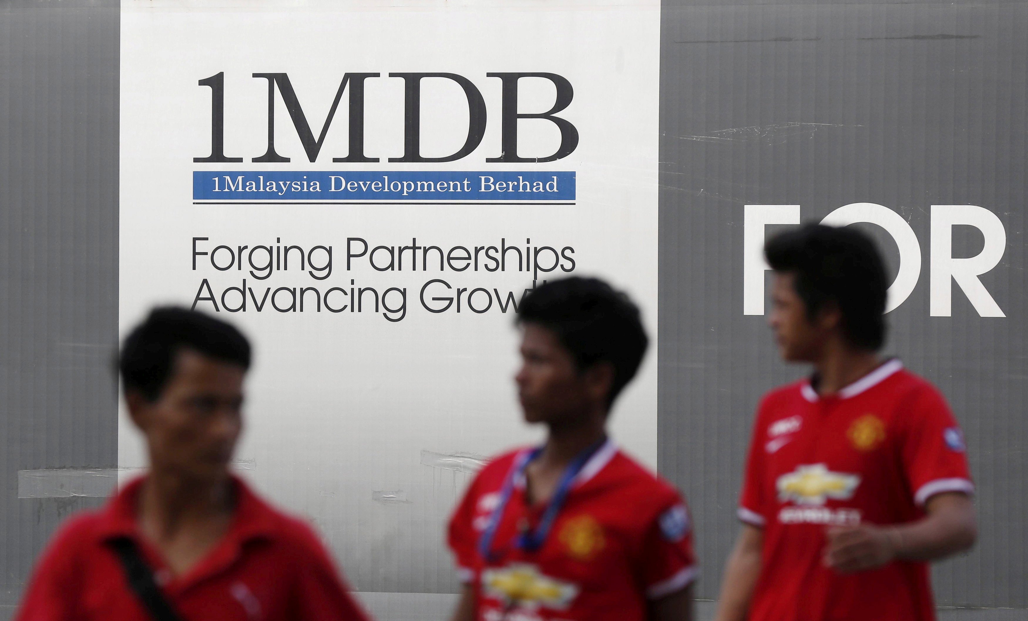 Men walk past a 1MDB billboard in Kuala Lumpur on March 1, 2015. Malaysian authorities say they have recouped about US$5 million in assets related to the 1MDB scandal. Photo: Reuters