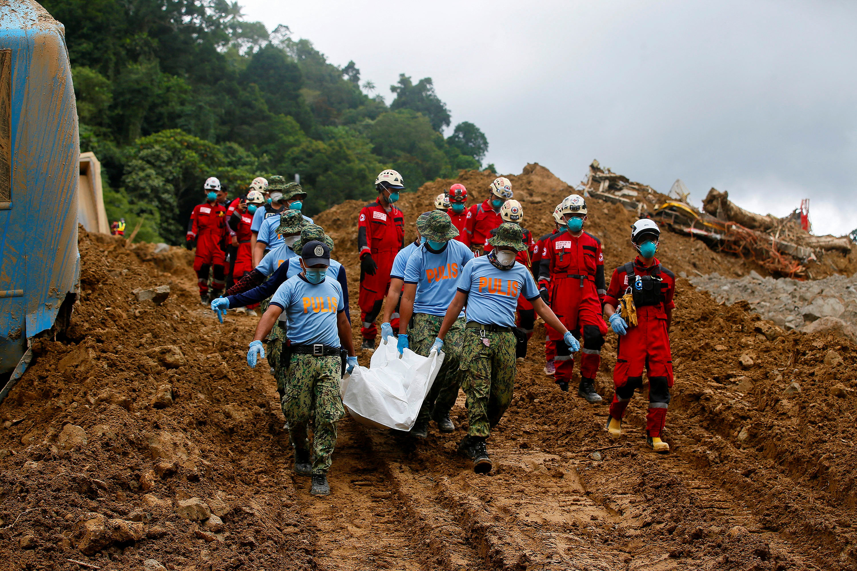 Police officers in the Philippines carry a body bag as the search for landslide survivors continues. Photo: Reuters