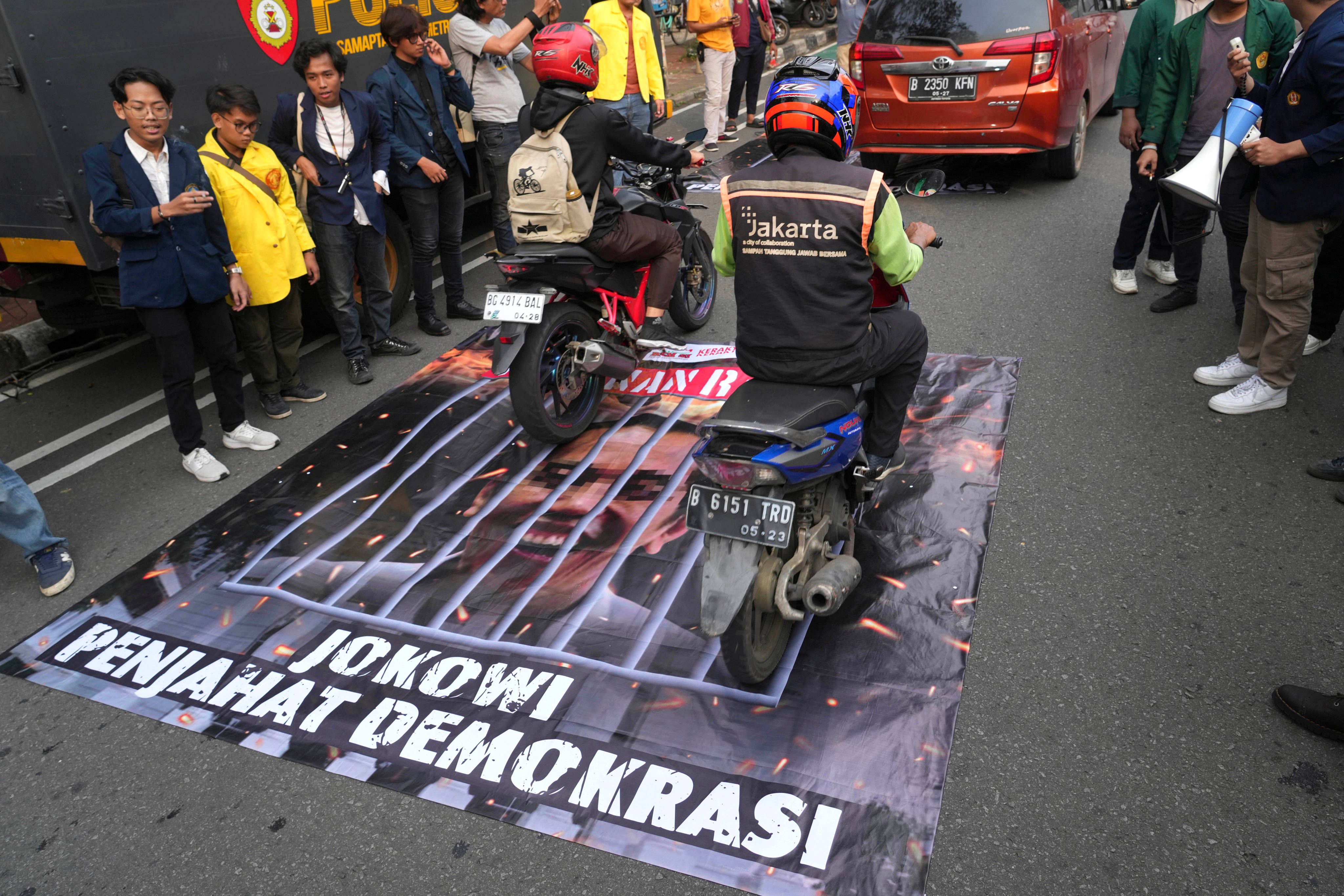 A banner with an image depicting Indonesian President Joko Widodo behind bars is laid out on the road during a rally demanding a fair presidential election. Students claim the president has been acting neutral in the election. Photo: AP