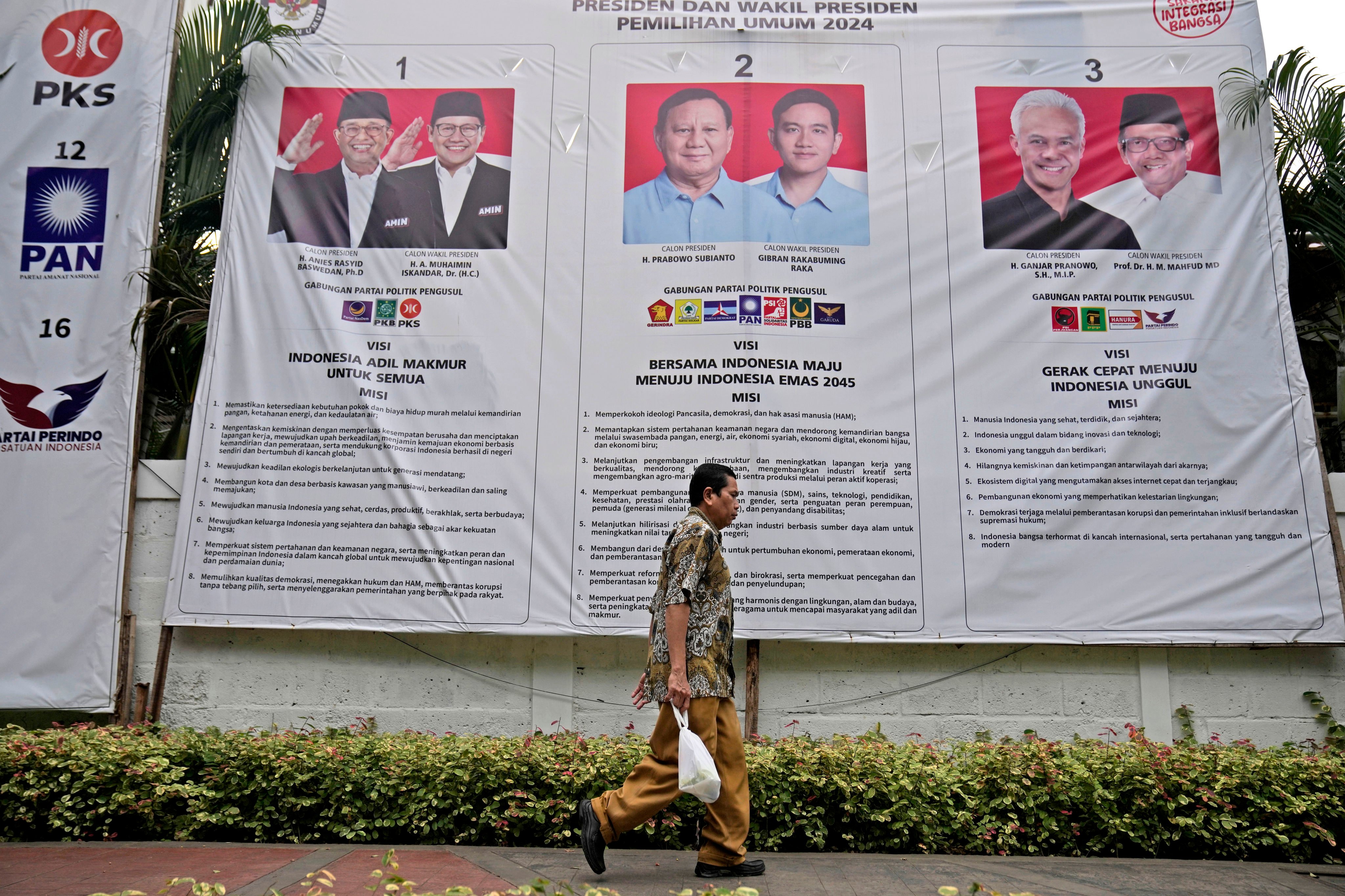 A man walks past an election banner in Jakarta introducing presidential candidates. Photo: AP