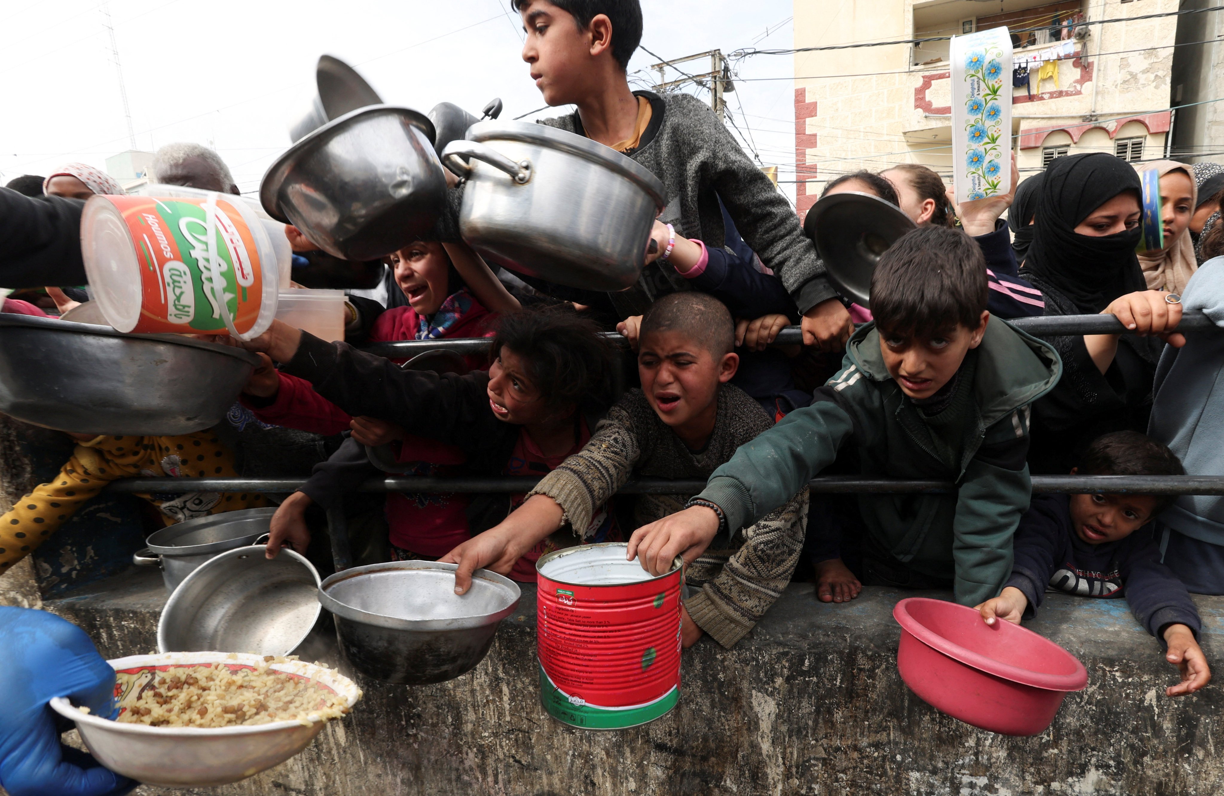 Palestinian children wait to receive food cooked by a charity kitchen in Rafah, in the southern Gaza Strip, on Tuesday. Photo: Reuters