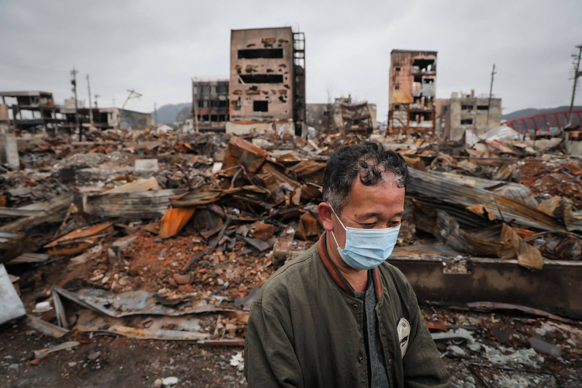 A man stands in front of his home destroyed by fire in the city of Wajima, Ishikawa prefecture on February 1, a month after a major earthquake struck the Noto region. Photo: AFP