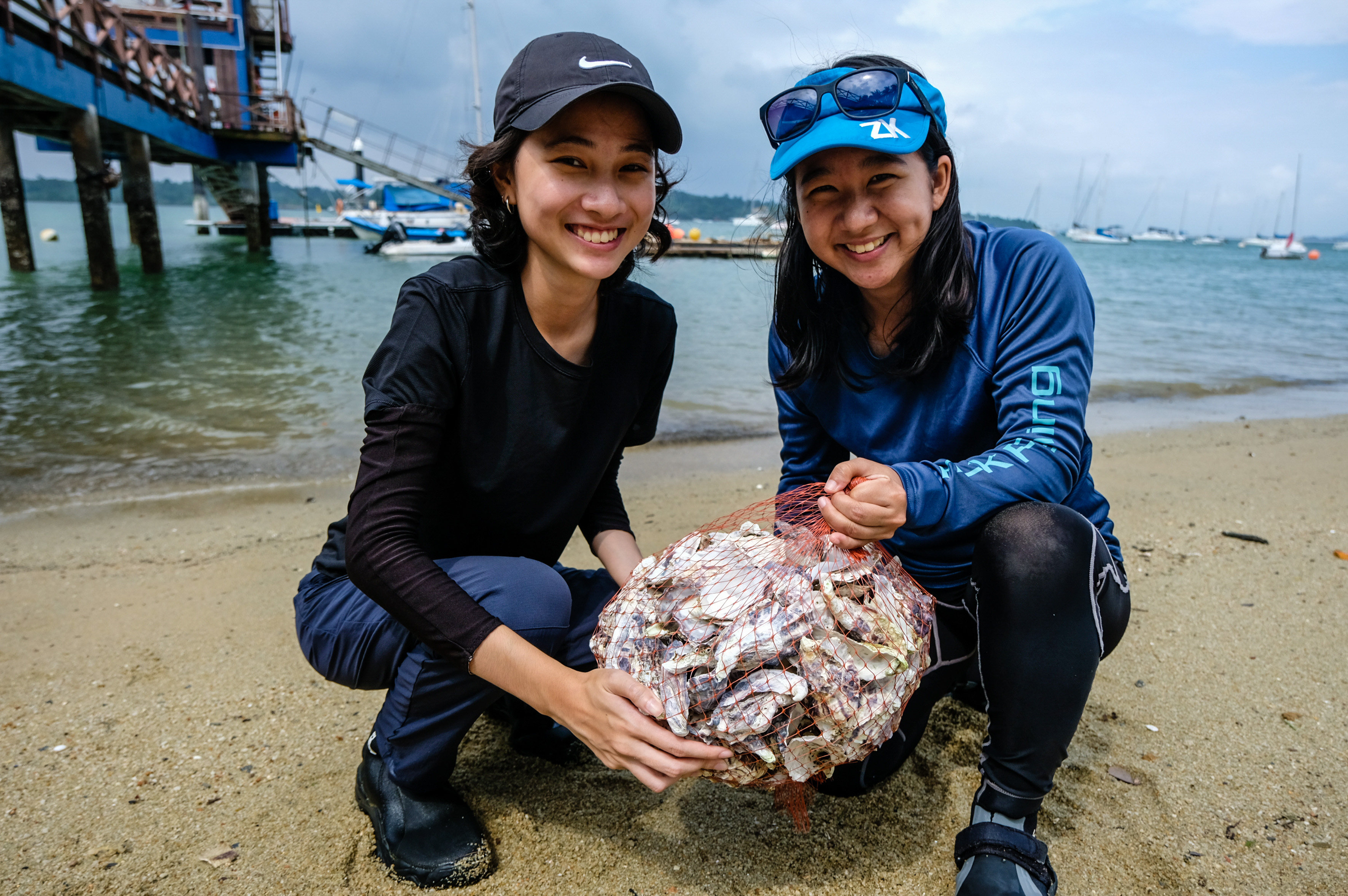 Ecologists Erika Ng (left) and Yukie Yokoyama with a reef bag of oyster shells at Changi Sailing Club. Photo: Toh Ee Ming