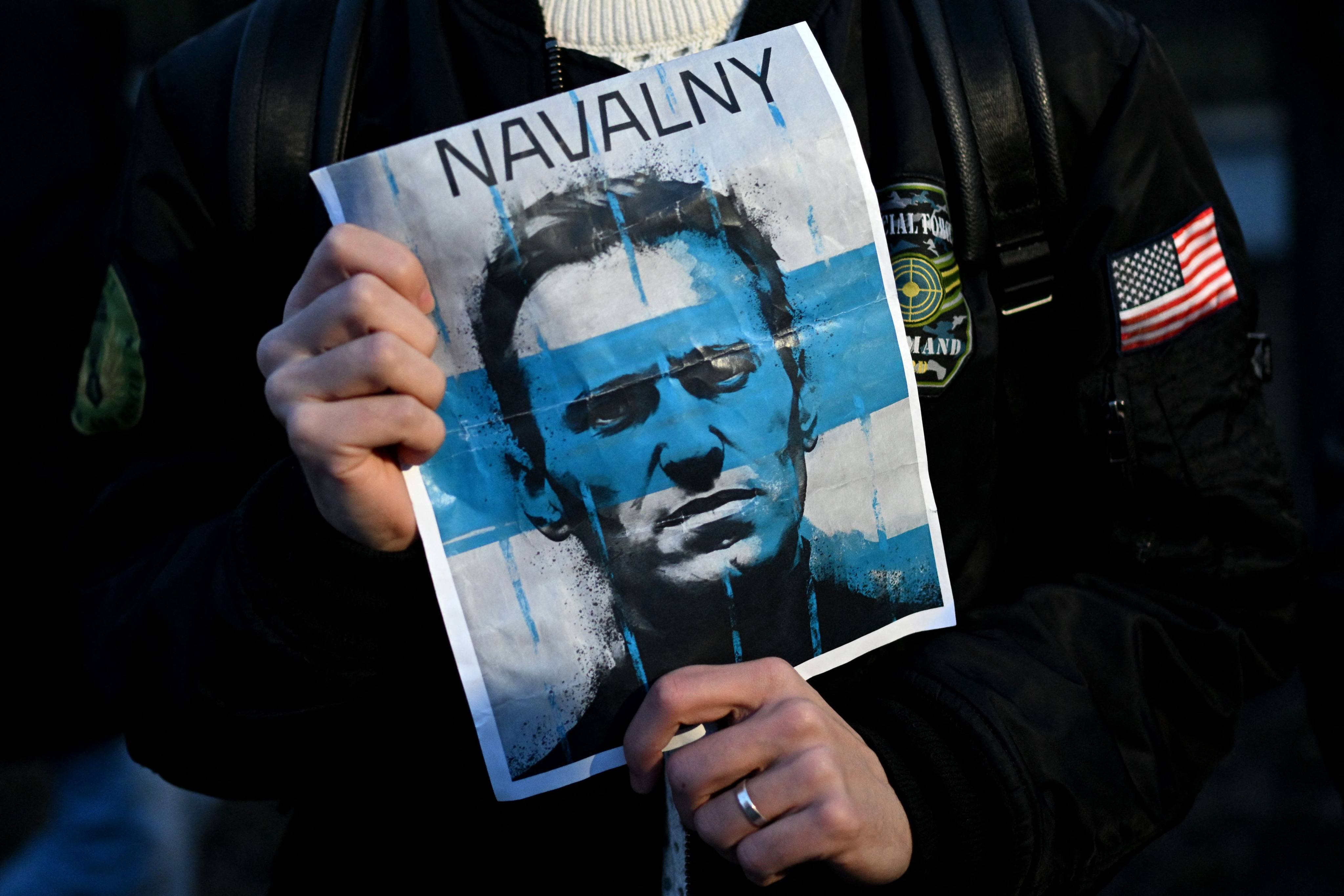 A demonstrator carries an image of late Russian opposition leader Alexei Navalny as people gather to protest in front of the Russian embassy in Warsaw on Friday. Photo: AFP