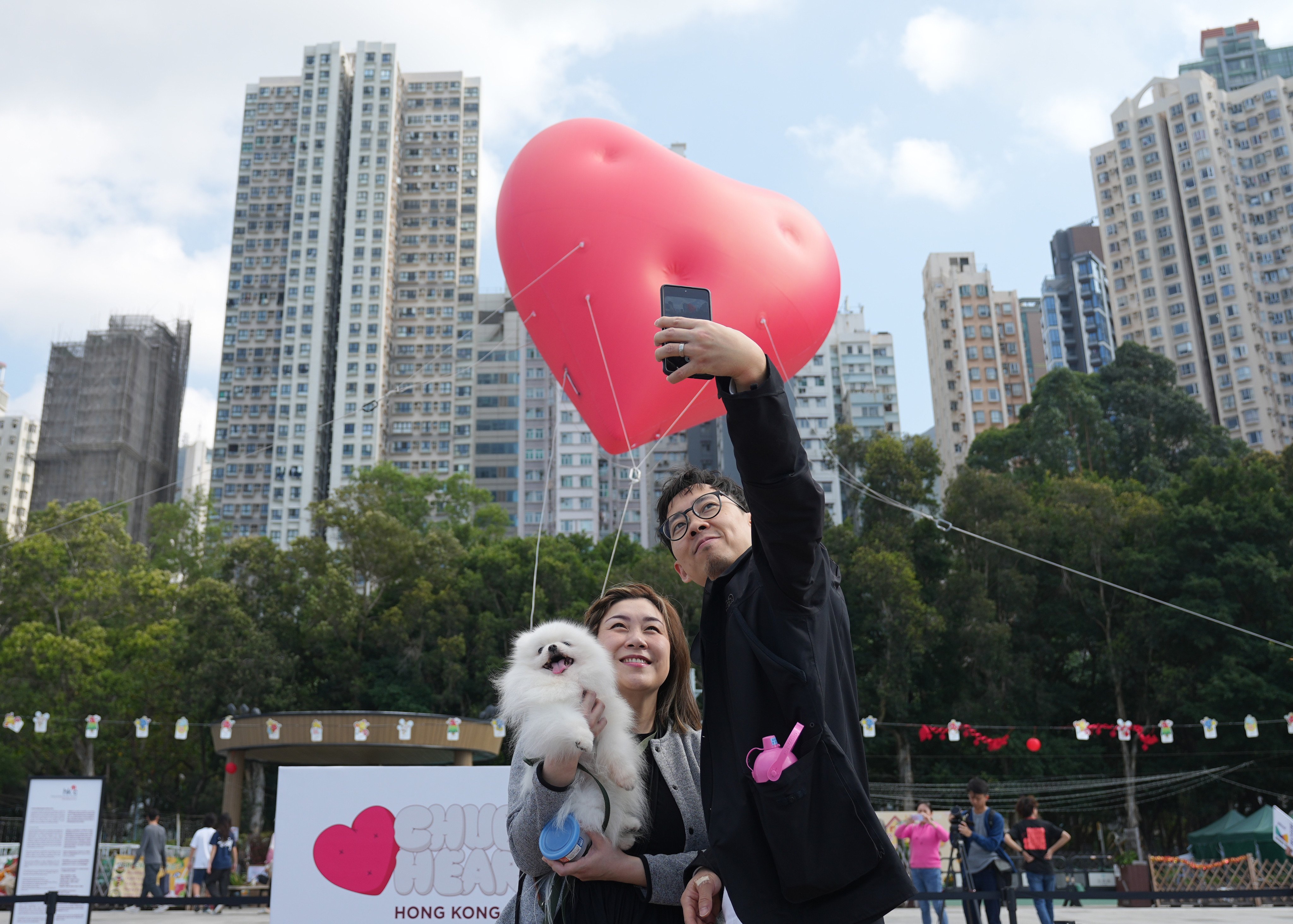 A couple pose with their dog in front of a  “Chubby Hearts” installation by fashion designer Anya Hindmarch in Kennedy Town on February 14. Photo: Eugene Lee