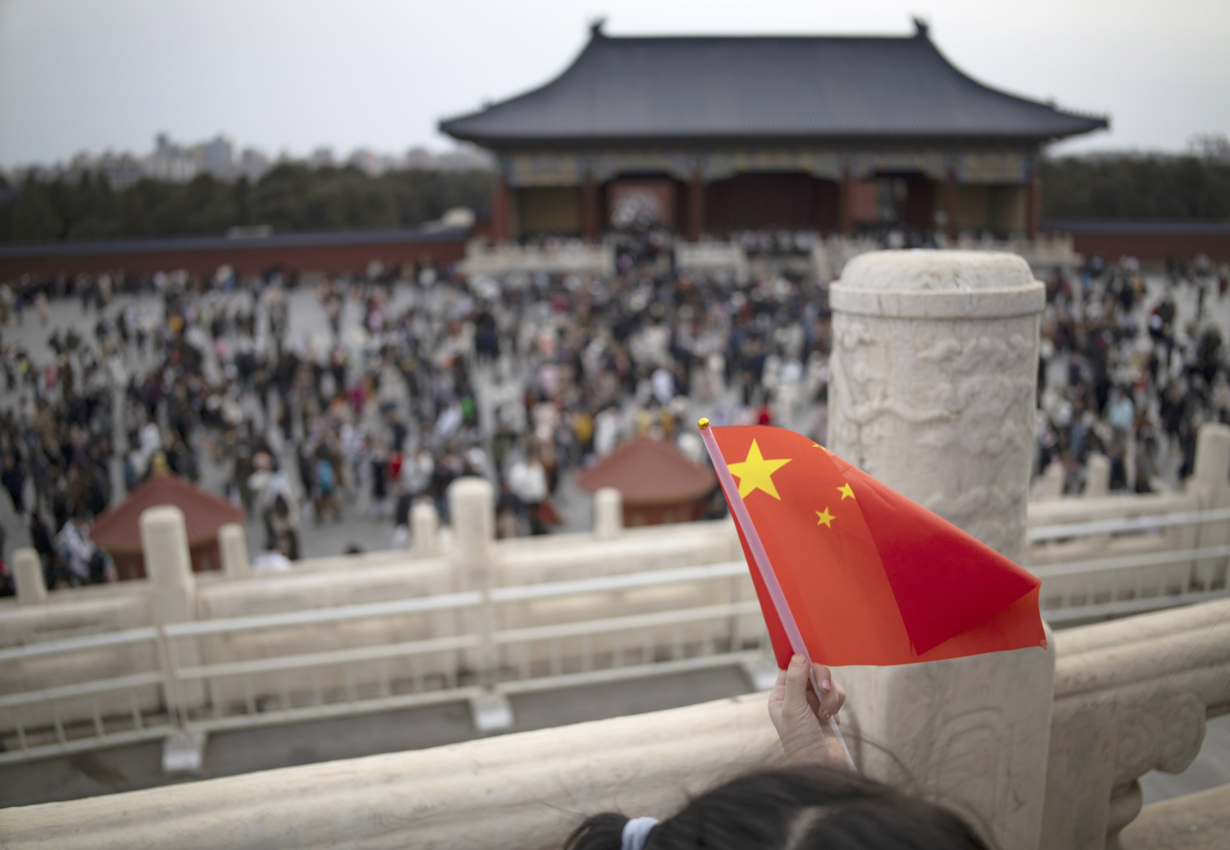 A girl holds a Chinese flag as visitors are seen in the background at the Temple of Heaven during celebrations of Chinese New Year in Beijing, February 14, 2024. Photo: EPA-EFE