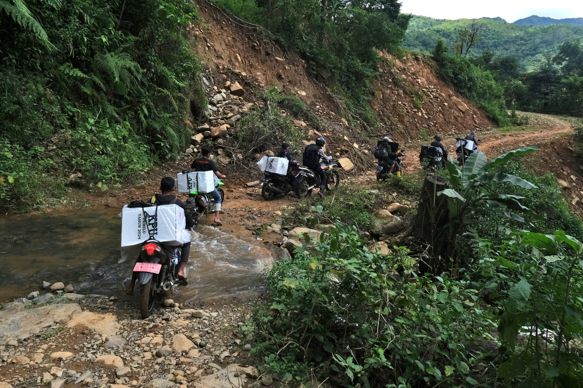 Electoral workers on motorbikes distribute ballot boxes and other election paraphernalia to polling stations in remote villages in Maros, Indonesia, ahead of the February 14 election. Photo: AP