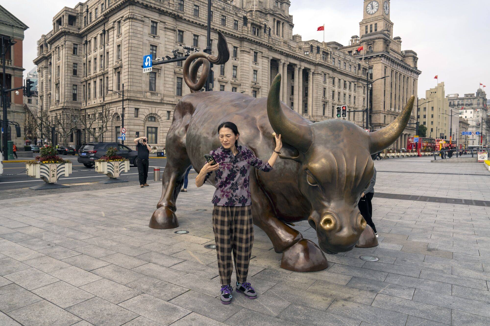 A woman poses for photographs with the Bund Bull in Shanghai on February 19. China’s 400 million-strong middle class is central to its future economic prosperity, creating an urgent need for reform to reverse trends of stagnant wages and rising fear of falling out of the middle class. Photo: Bloomberg