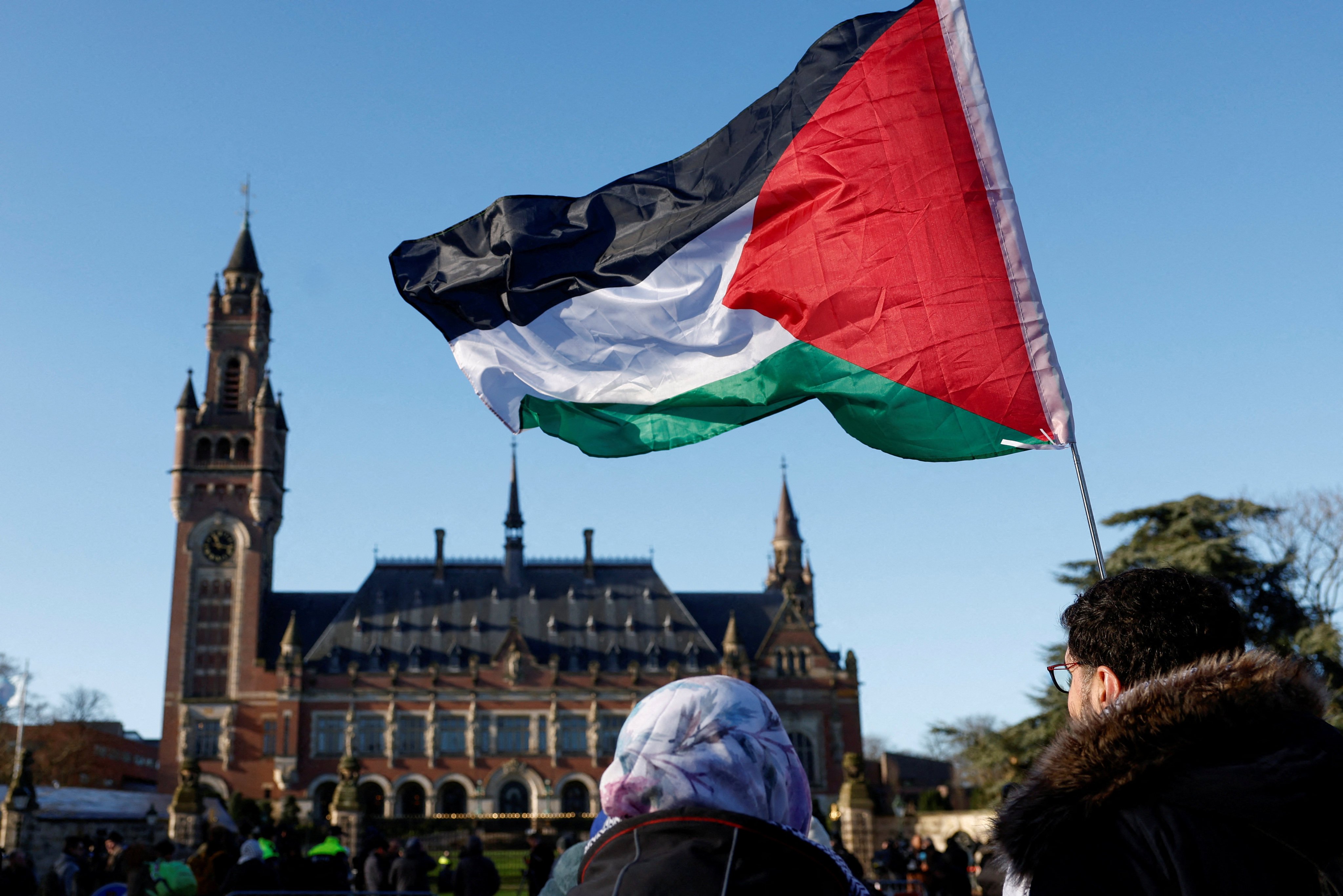Protesters hold a Palestinian flag as they gather outside the International Court of Justice in The Hague, Netherlands. Photo: Reuters