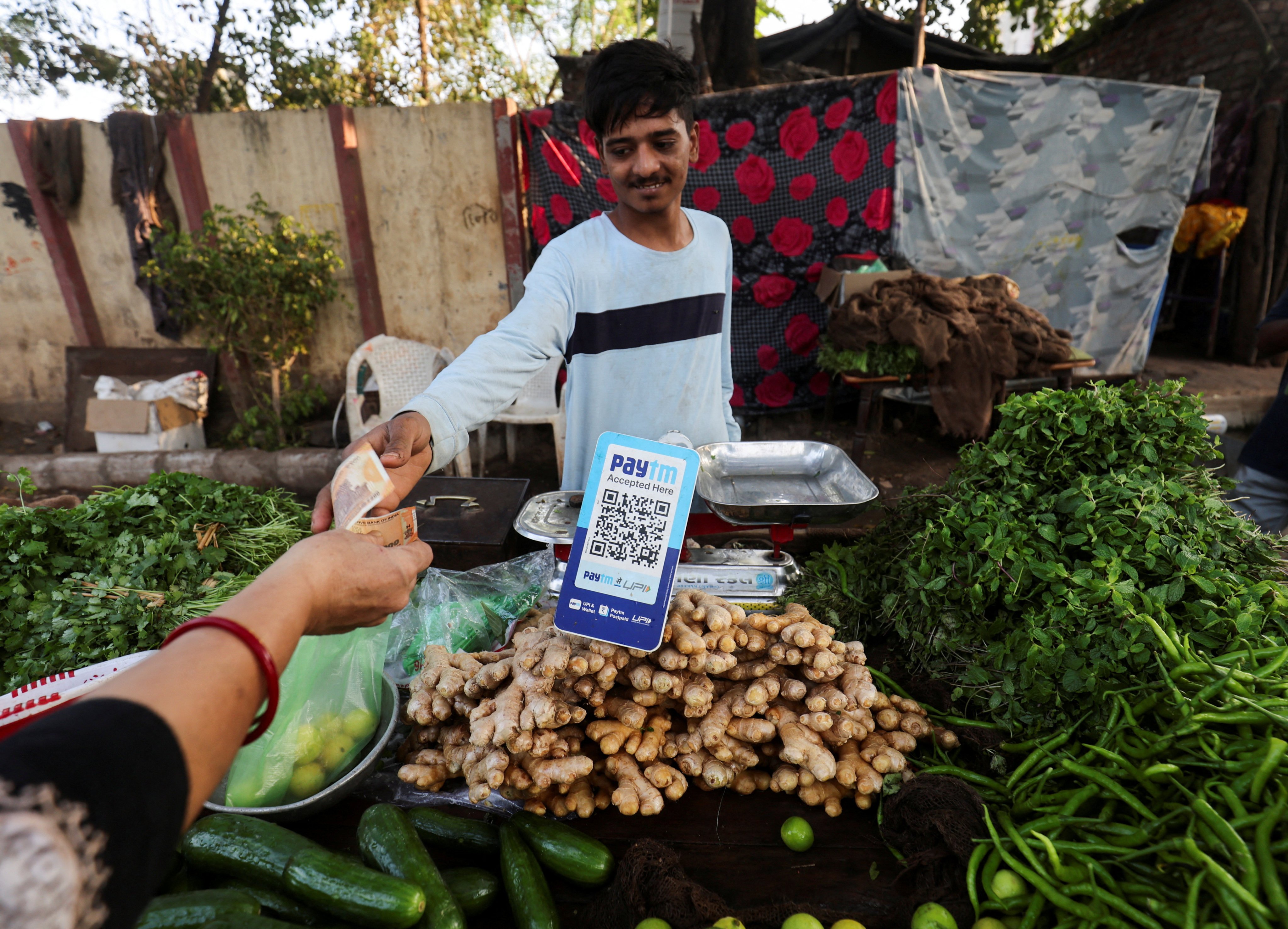 A customer pays cash to buy vegetables next to a QR code of Paytm, a digital payments firm, in Ahmedabad. Analysts anticipate more challenges in India’s tech sector in the coming months. Photo: Reuters