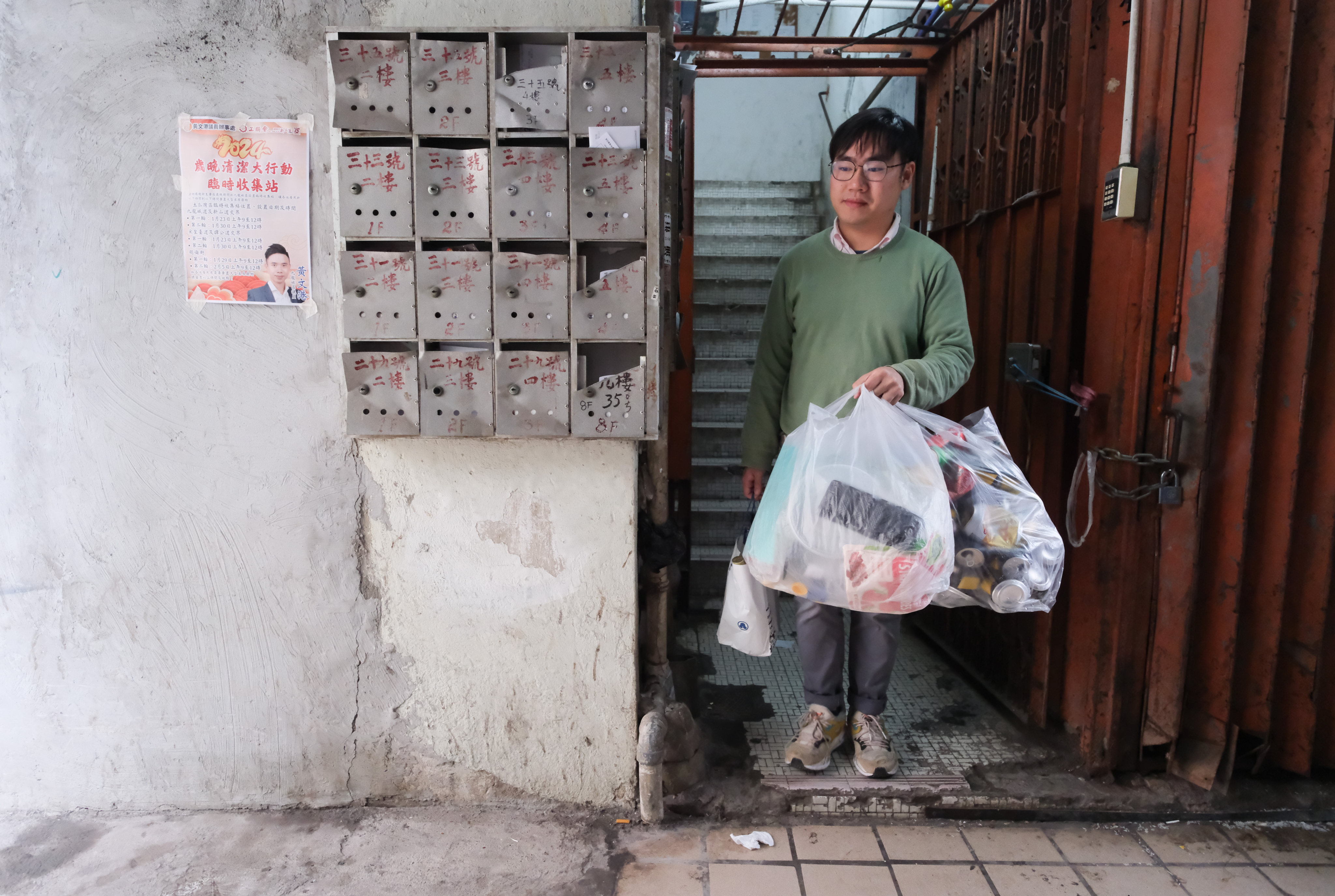 A resident of a “three-nil building” takes recyclable waste to a community recycling station. To encourage waste reduction and recycling, recycling bins should be conveniently located and recycling station operating hours extended. Photo: Sun Yeung

