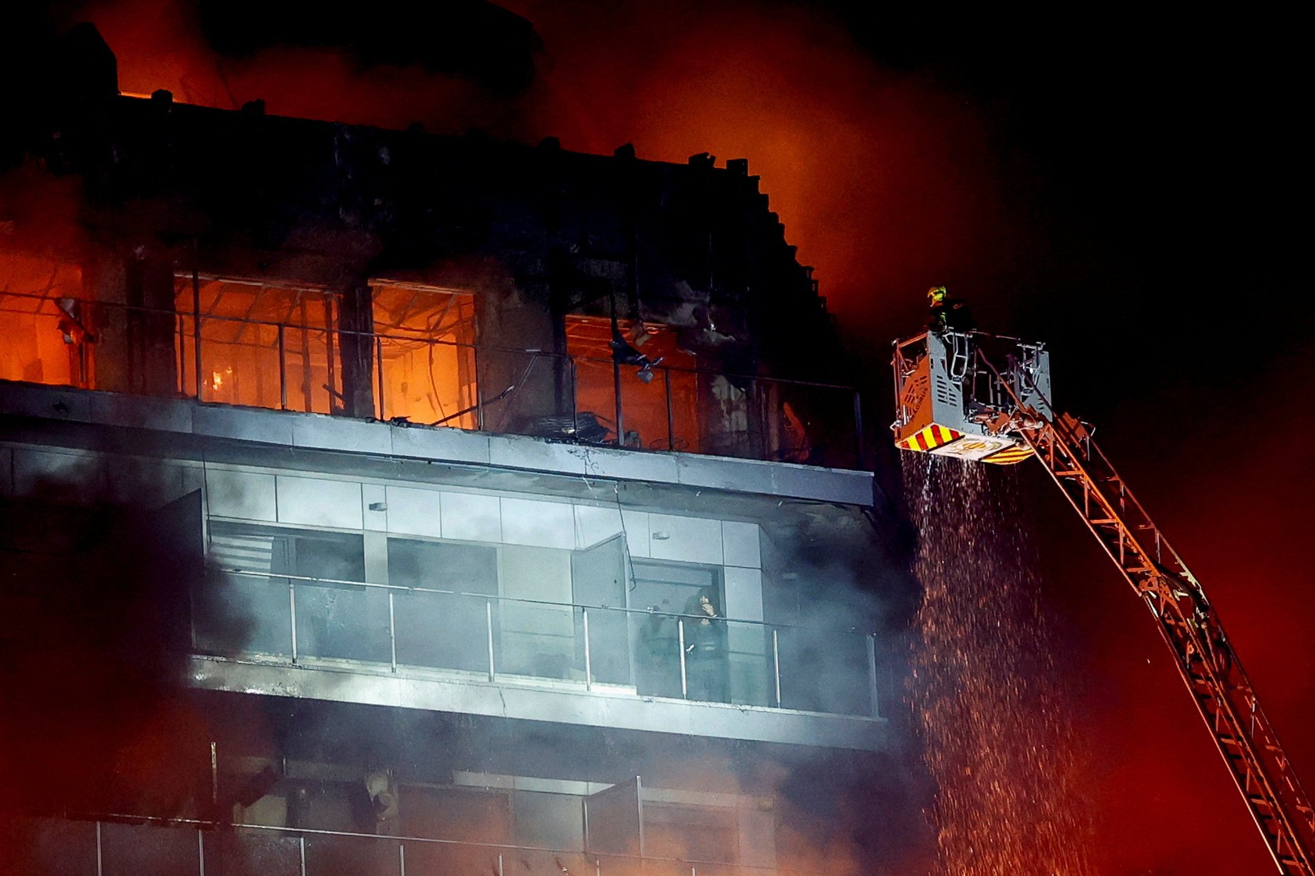 A man waits to be rescued by firefighters from a fire in Valencia. Photo: Reuters