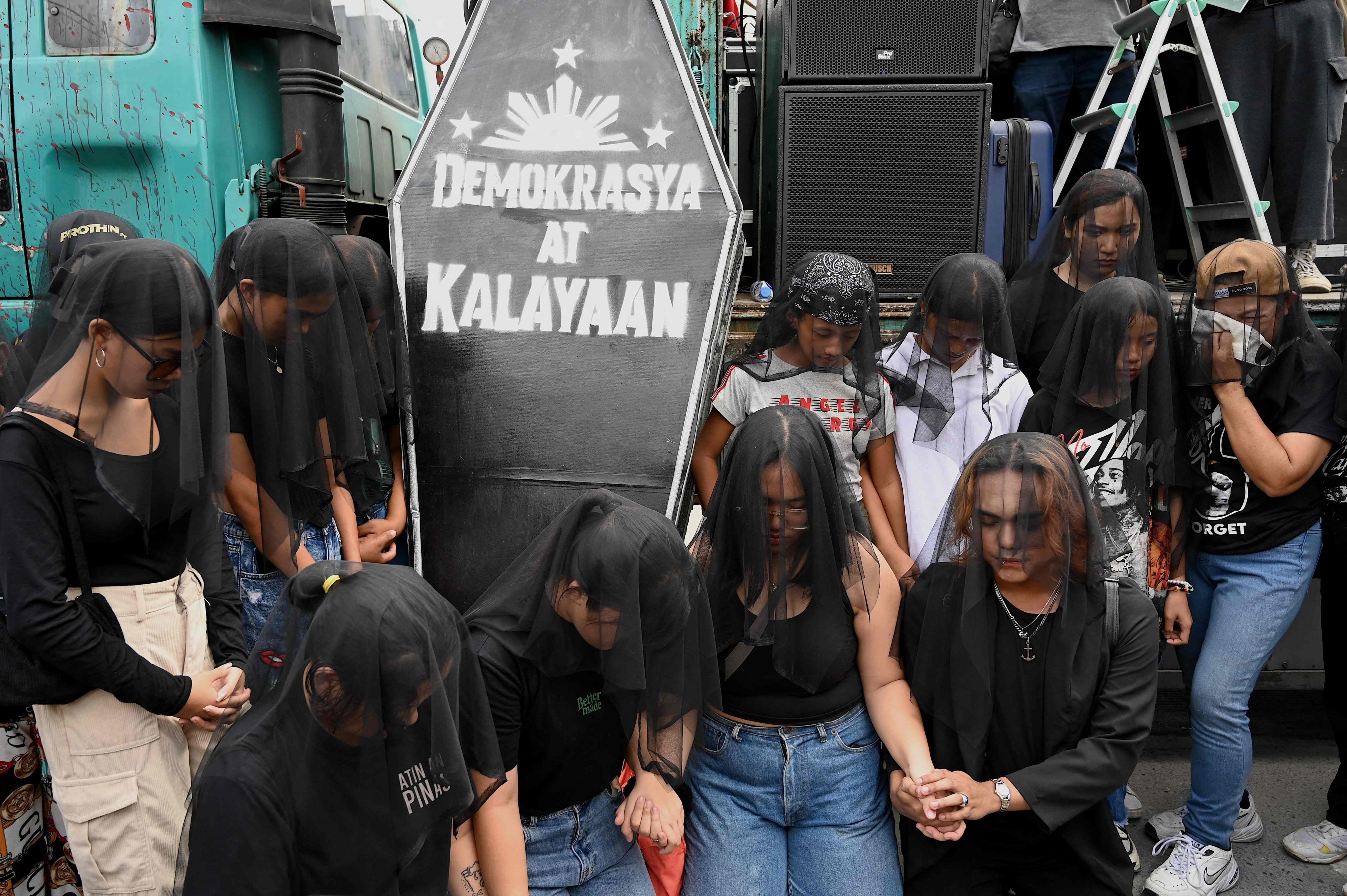 Protesters in Quezon City grieve with a makeshift coffin with words reading ‘Democracy’ and ‘Peace’ during a demonstration commemorating the 38th anniversary of the revolution which ousted Philippine President Ferdinand Marcos Jnr’s dictator father and sent the family into exile. Photo: AFP
