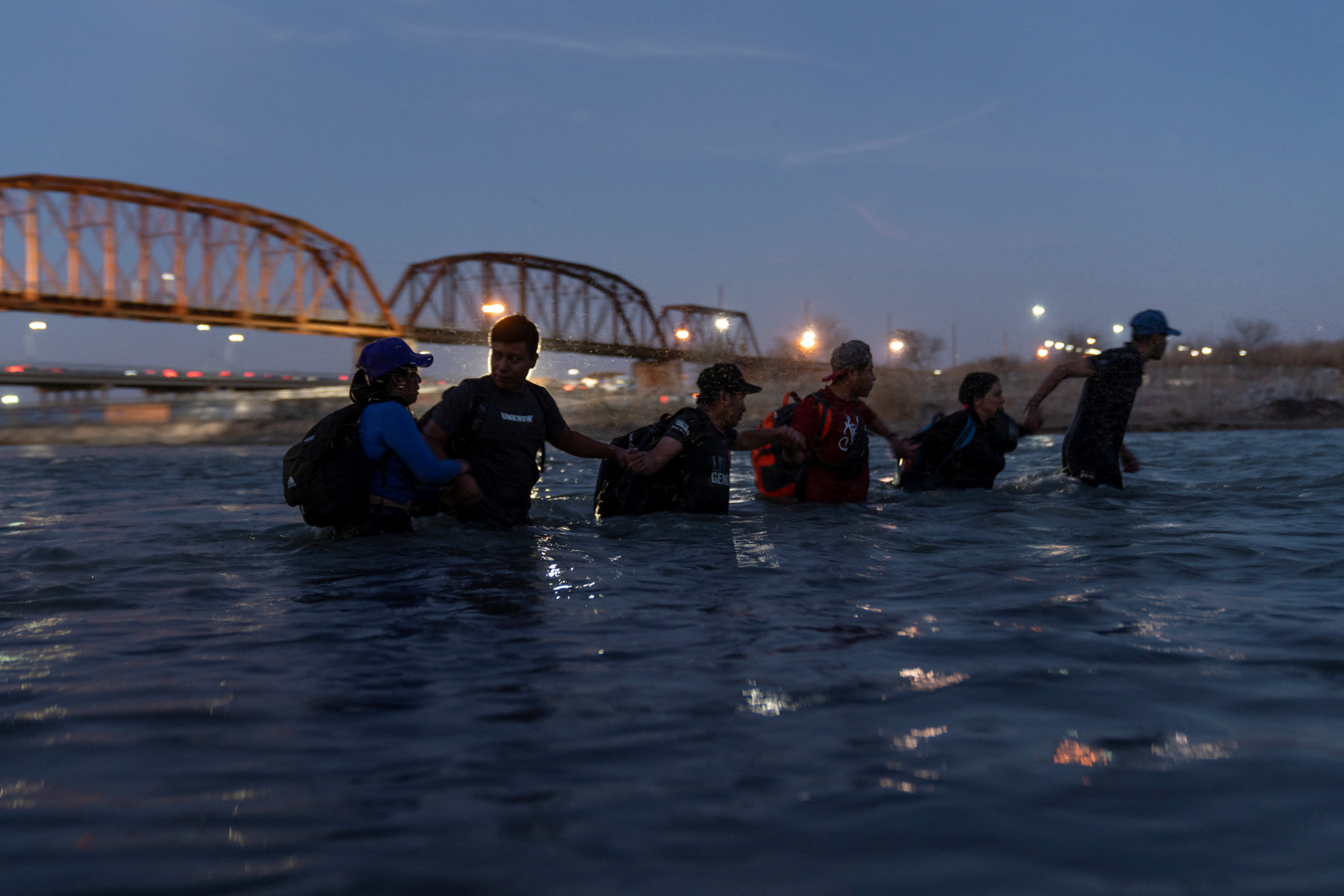 Migrants link arms as they wade into the Rio Grande river from Piedras Negras, Coahuila, Mexico with intentions to cross into Eagle Pass, Texas, US on Saturday. Photo: Reuters