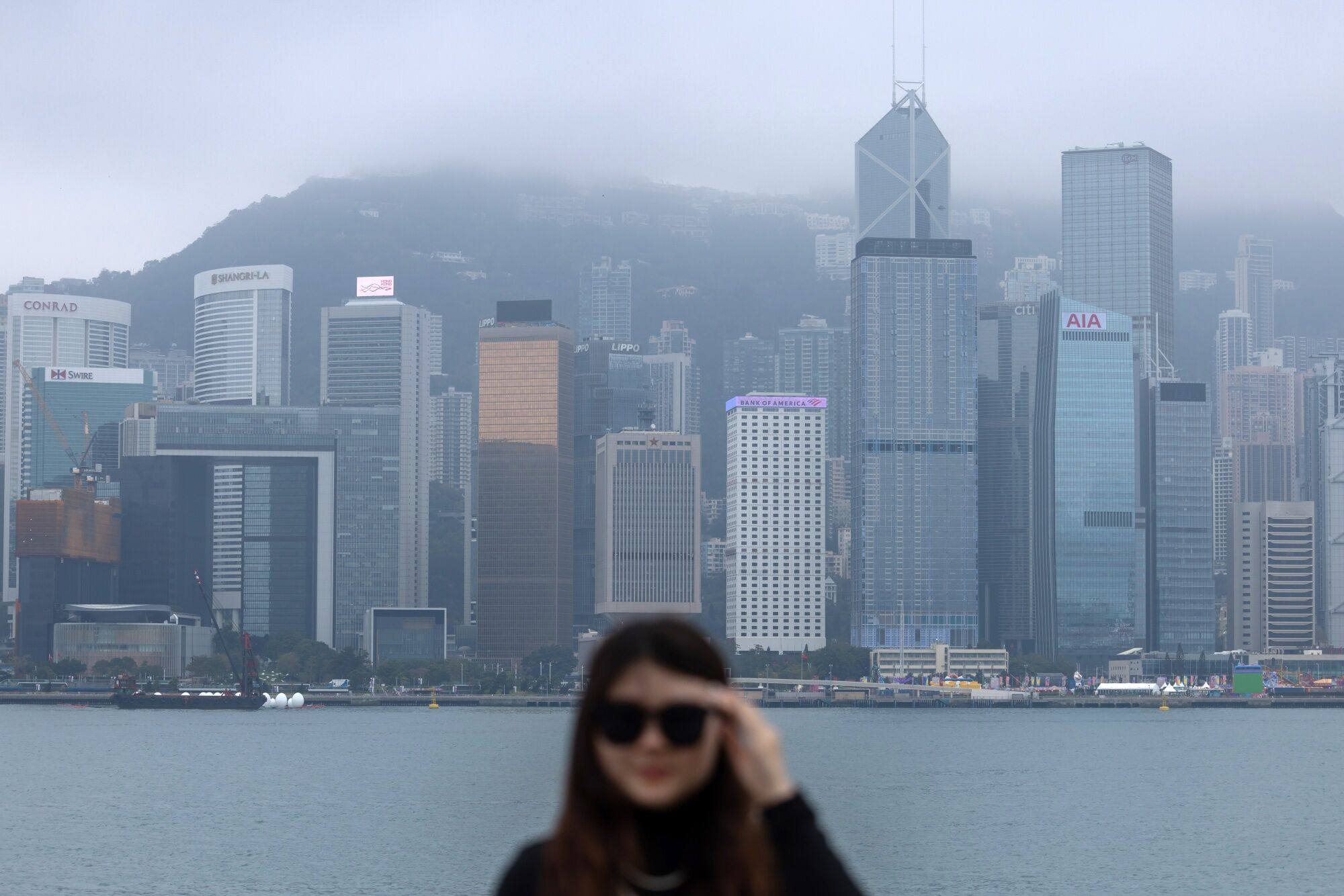 A tourist at the Tsim Sha Tsui promenade, with Hong Kong’s Central district across Victoria Harbour behind her, on January 30. Photo: Bloomberg