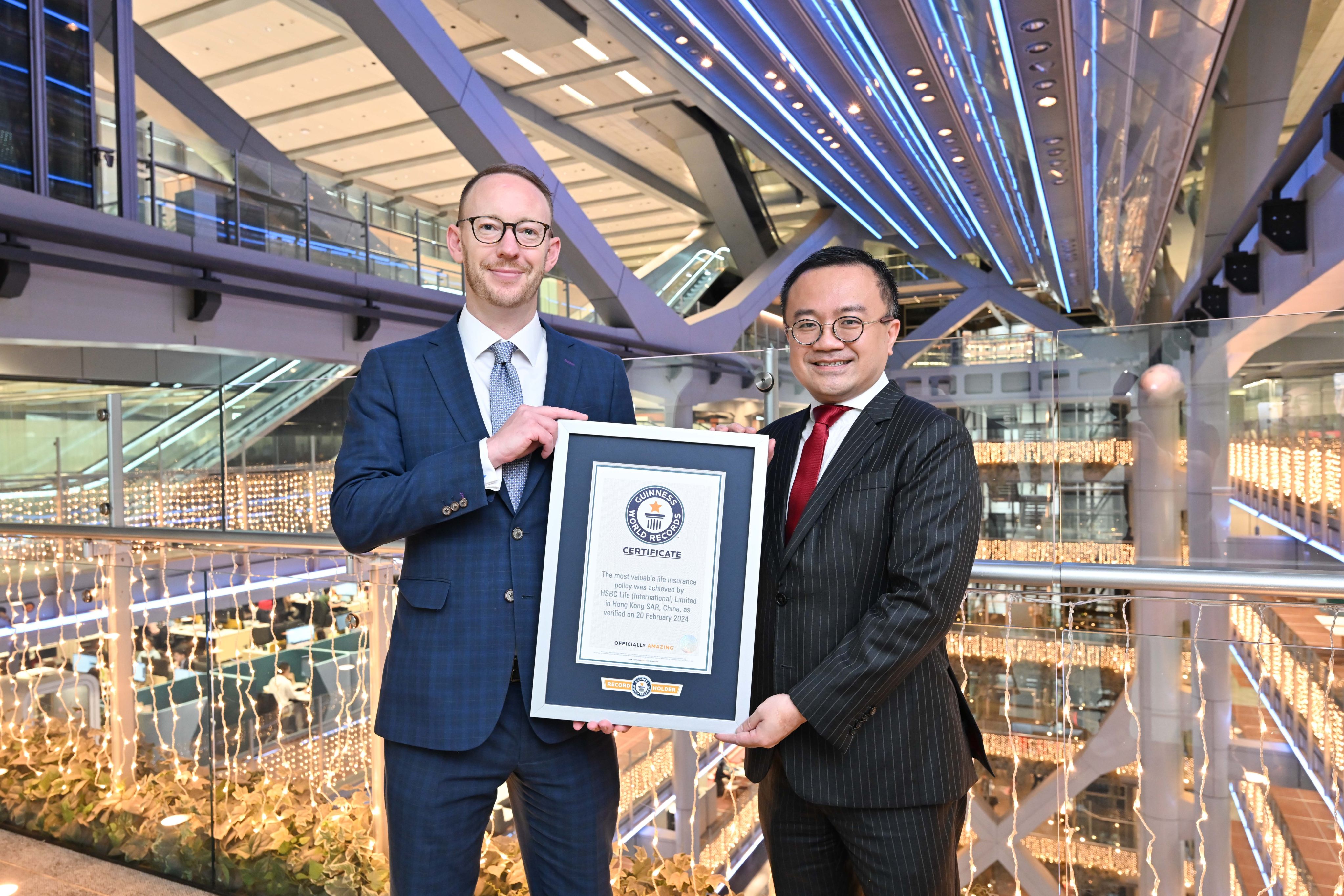 Edward Moncreiffe (left), CEO of HSBC Life Hong Kong and Macau, and K C Cheung, head of products, display a certificate from Guinness World Records for the all-time high insurance policy sale. Photo: Handout