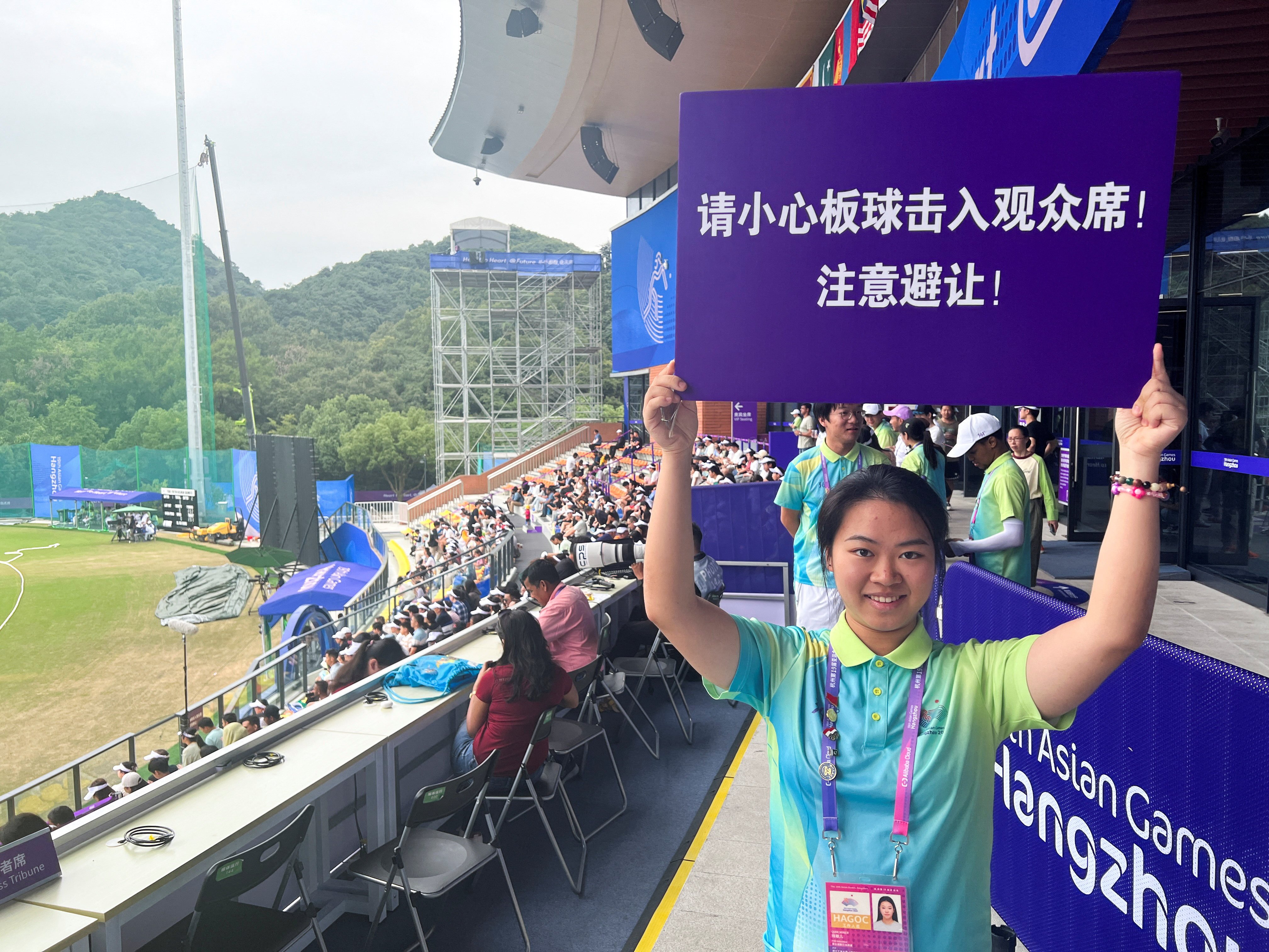 An Asian Games volunteer holds a sign warning spectators to beware of cricket balls being hit into the terraces during the quarter-final between India and Nepal in Hangzhou. Photo: Reuters