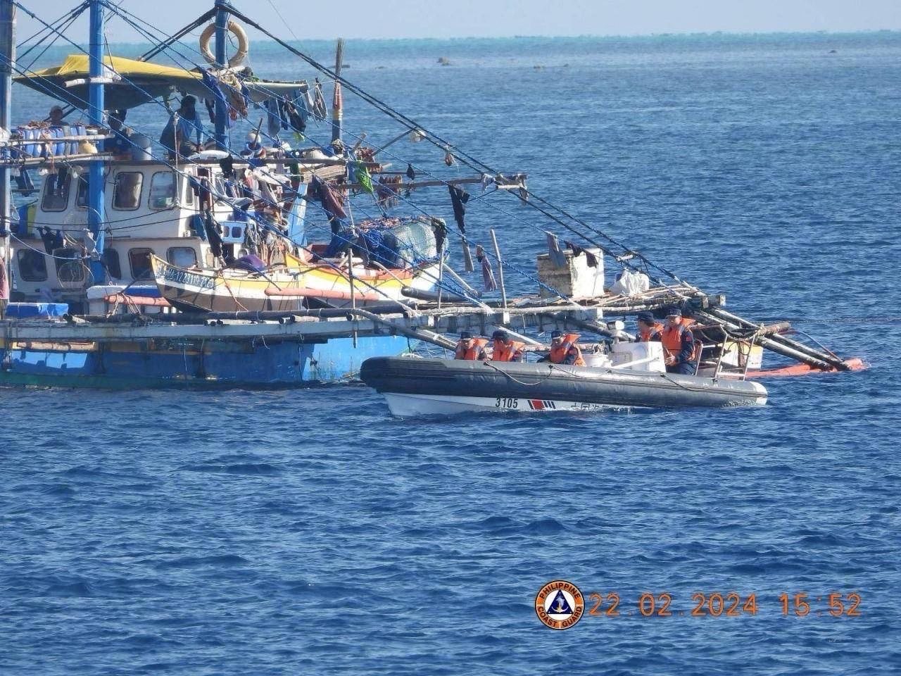 China Coast Guard personnel onboard a rigid-hulled inflatable boat, right, are seen shadowing a Philippine fishing boat near the Scarborough Shoal on February 22. Photo: PCG/AFP