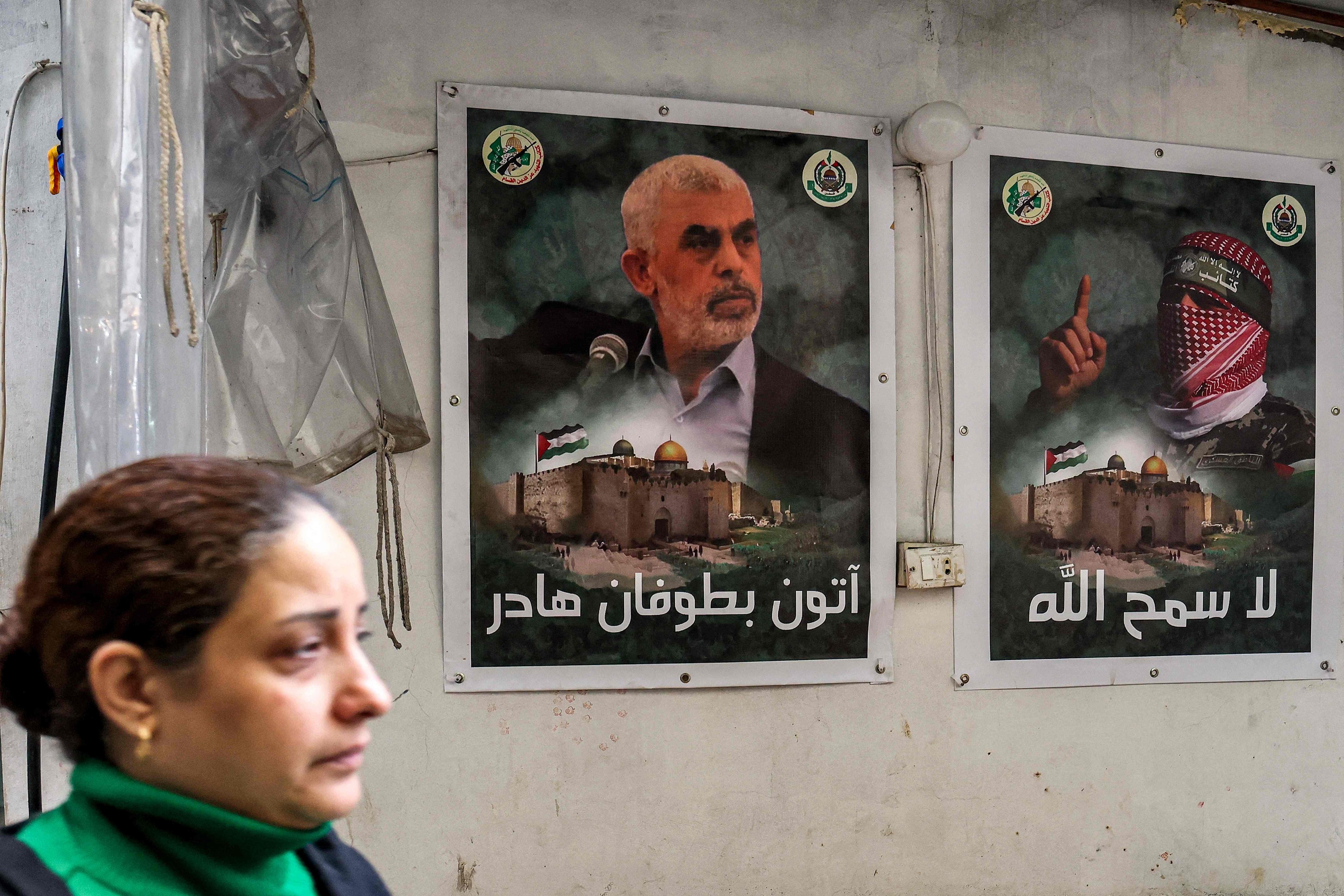 On February 5, a woman in the Burj al-Barajneh refugee camp in Beirut, Lebanon walks past posters depicting Yahya Sinwar, head of the political wing of Hamas, and Abu Obeida, the masked spokesperson of the Ezzedeen al-Qassam Brigades (Hamas’ armed wing). Photo: AFP