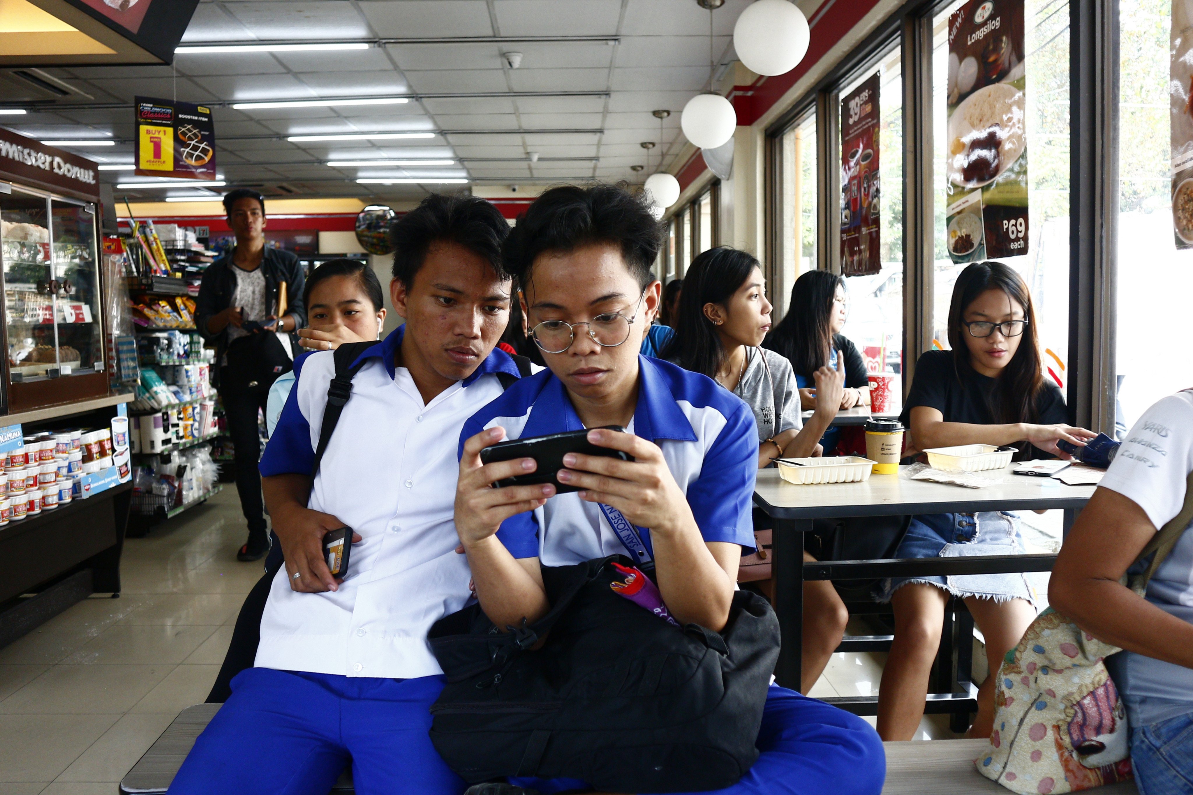 Filipino teenagers look at a smartphone at a convenience store. Photo: Shutterstock