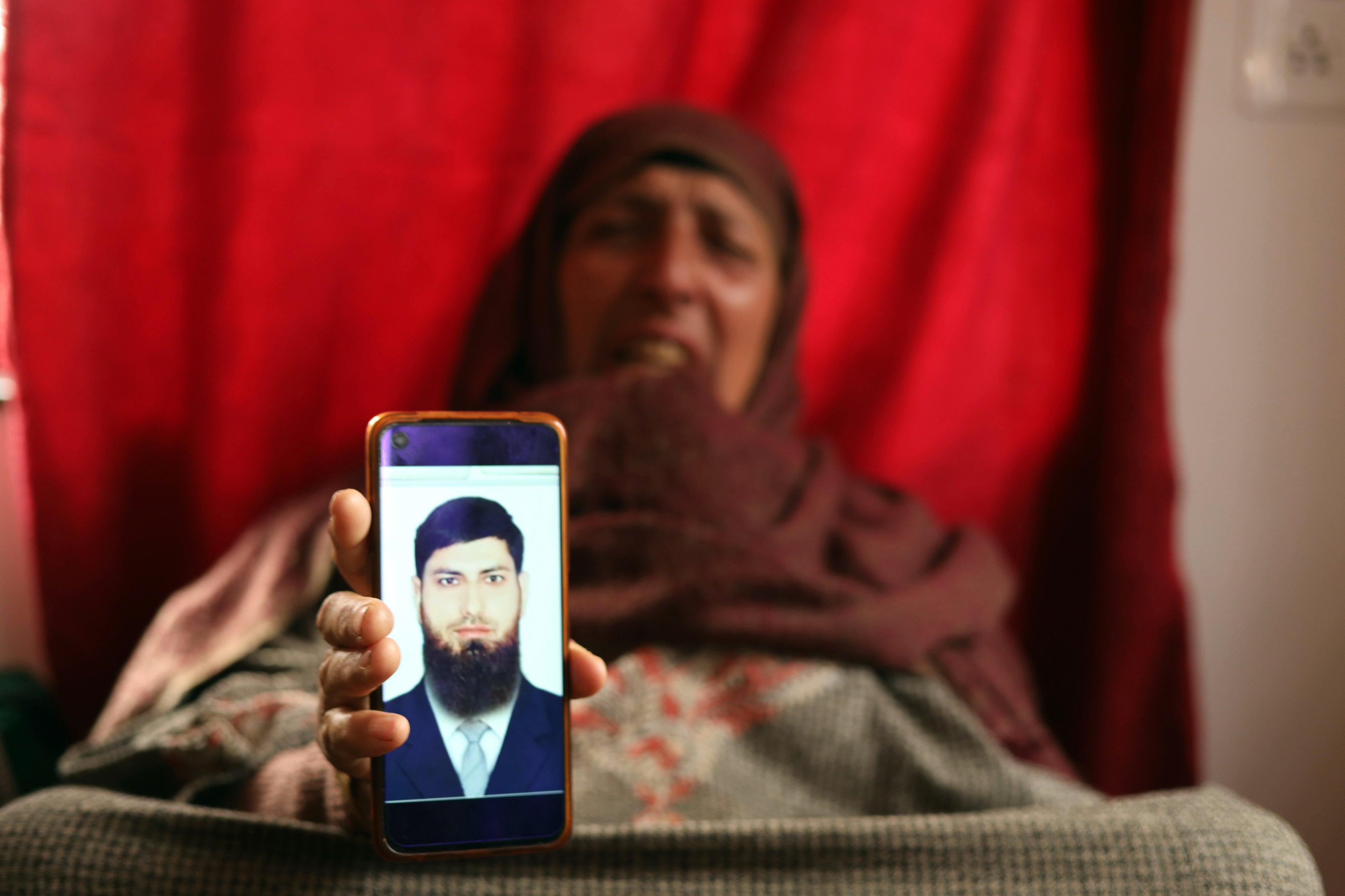 The mother of Aazad Yusuf Kumar, from a village in Indian Kashmir, shows his picture. Photo: Kamran Yousuf