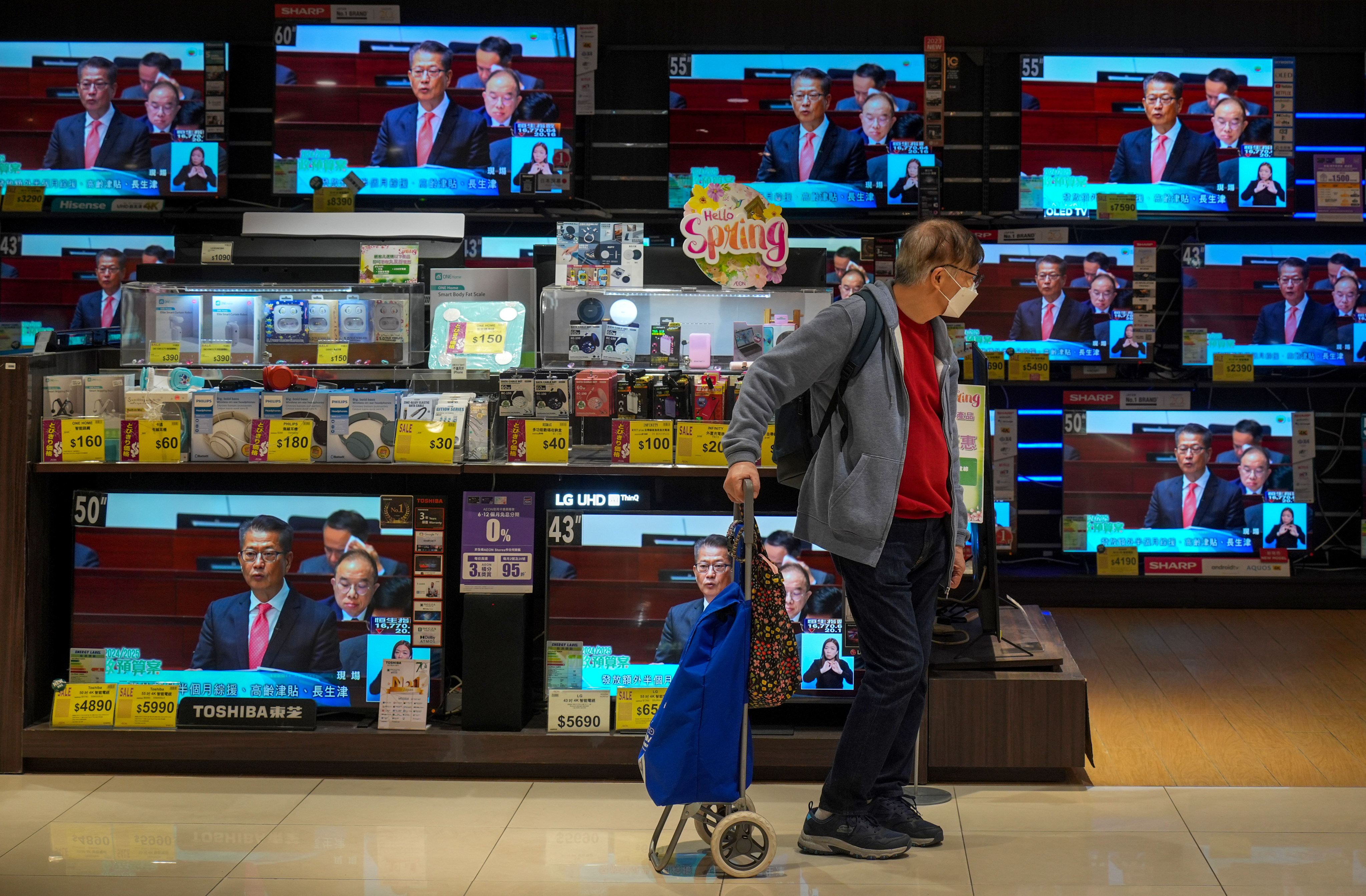 A man walks by televisions broadcasting the financial secretary’s budget speech at an electronics store in Tai Koo on February 28. Photo: Eugene Lee