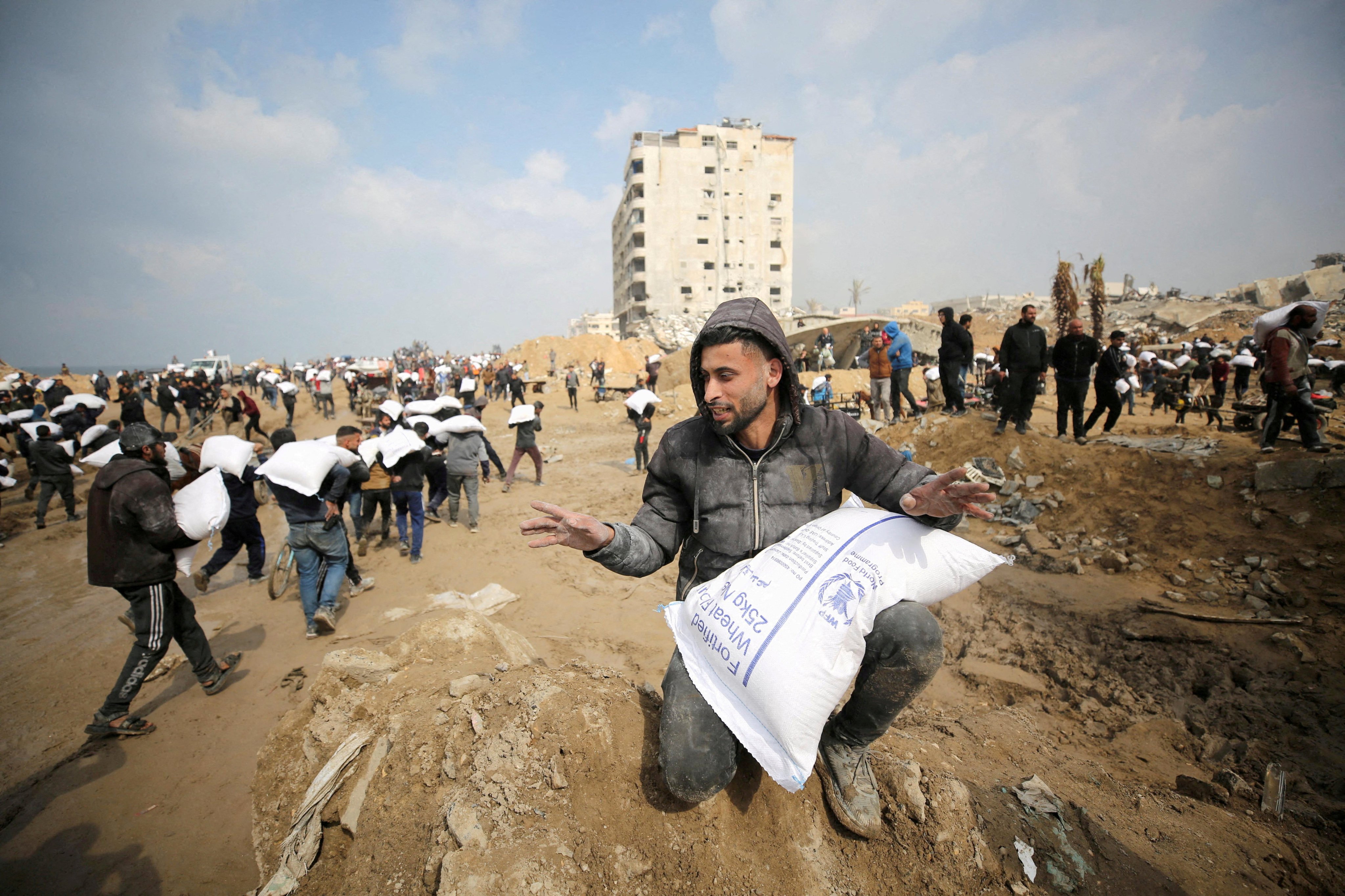 Palestinians carry bags of flour from an aid truck near an Israeli checkpoint on February 19. Photo: Reuters