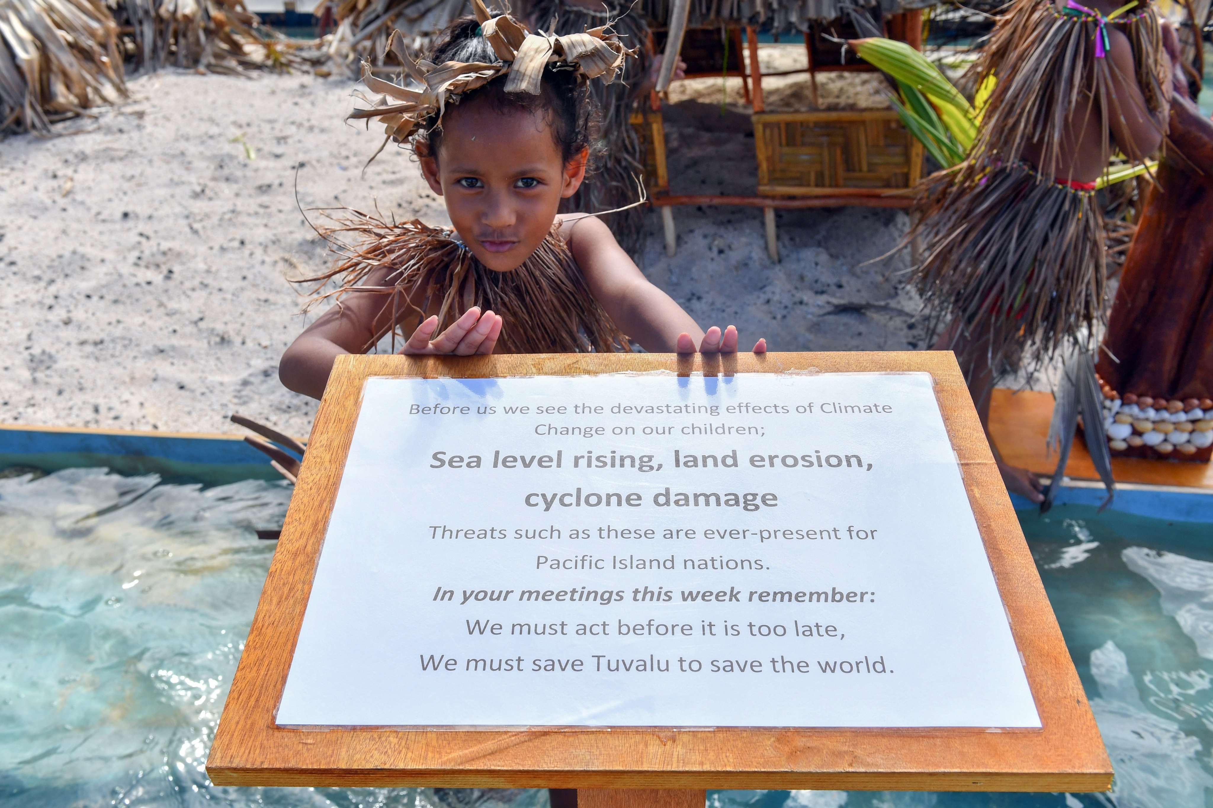A child welcomes delegates to the Pacific Islands Forum on August 14, 2019, in Funafuti, Tuvalu, a sinking island nation. Even the global disaster of climate warming affects different geographies differently. There is no development model that fits all nations. Photo: EPA-EFE
