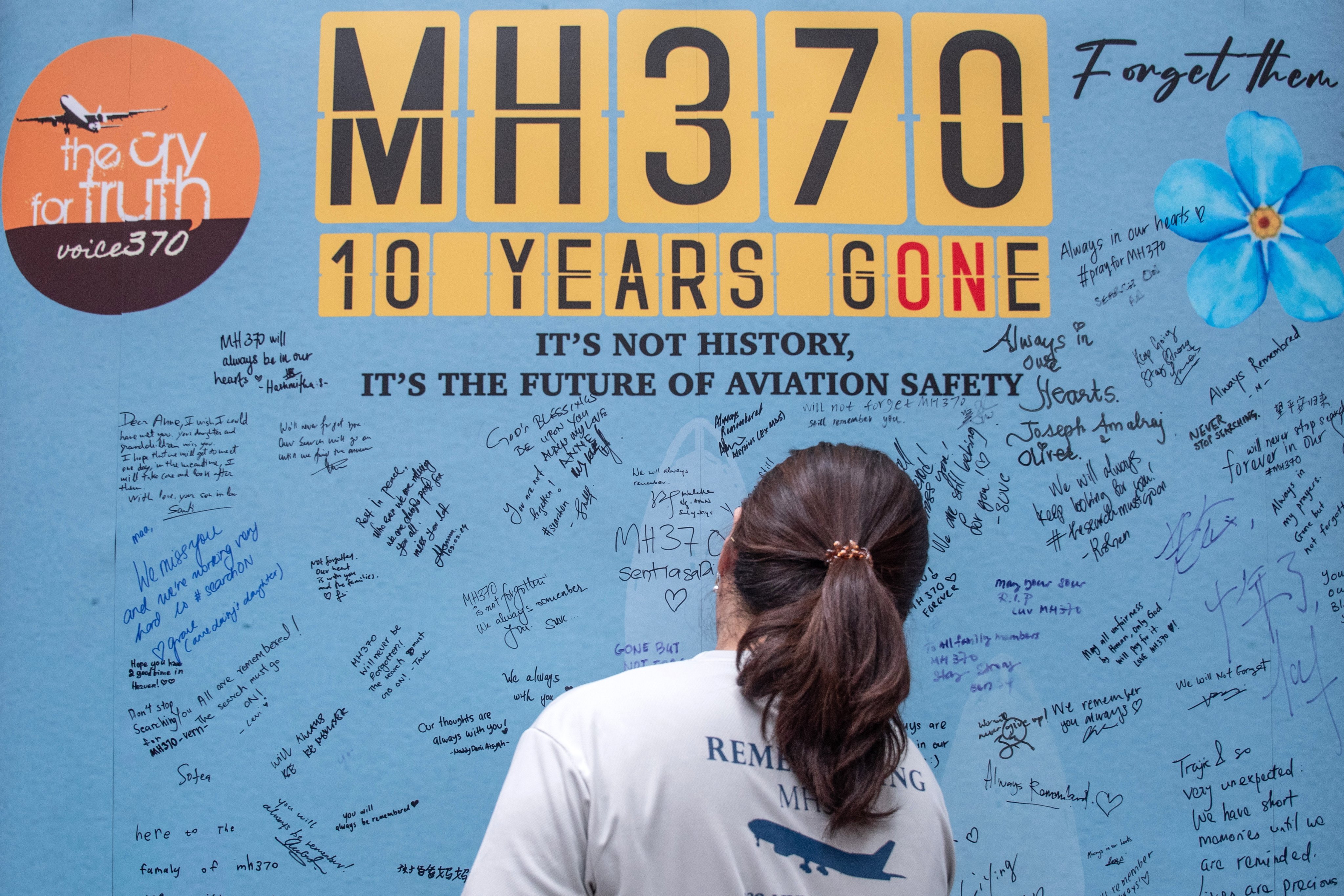 A family member of passengers and crew on board the missing Malaysian Airlines flight MH370 writes on a memorial wall during a remembrance event marking the 10th anniversary of its disappearance in Selangor, Malaysia, on March 3. Photo: EPA-EFE