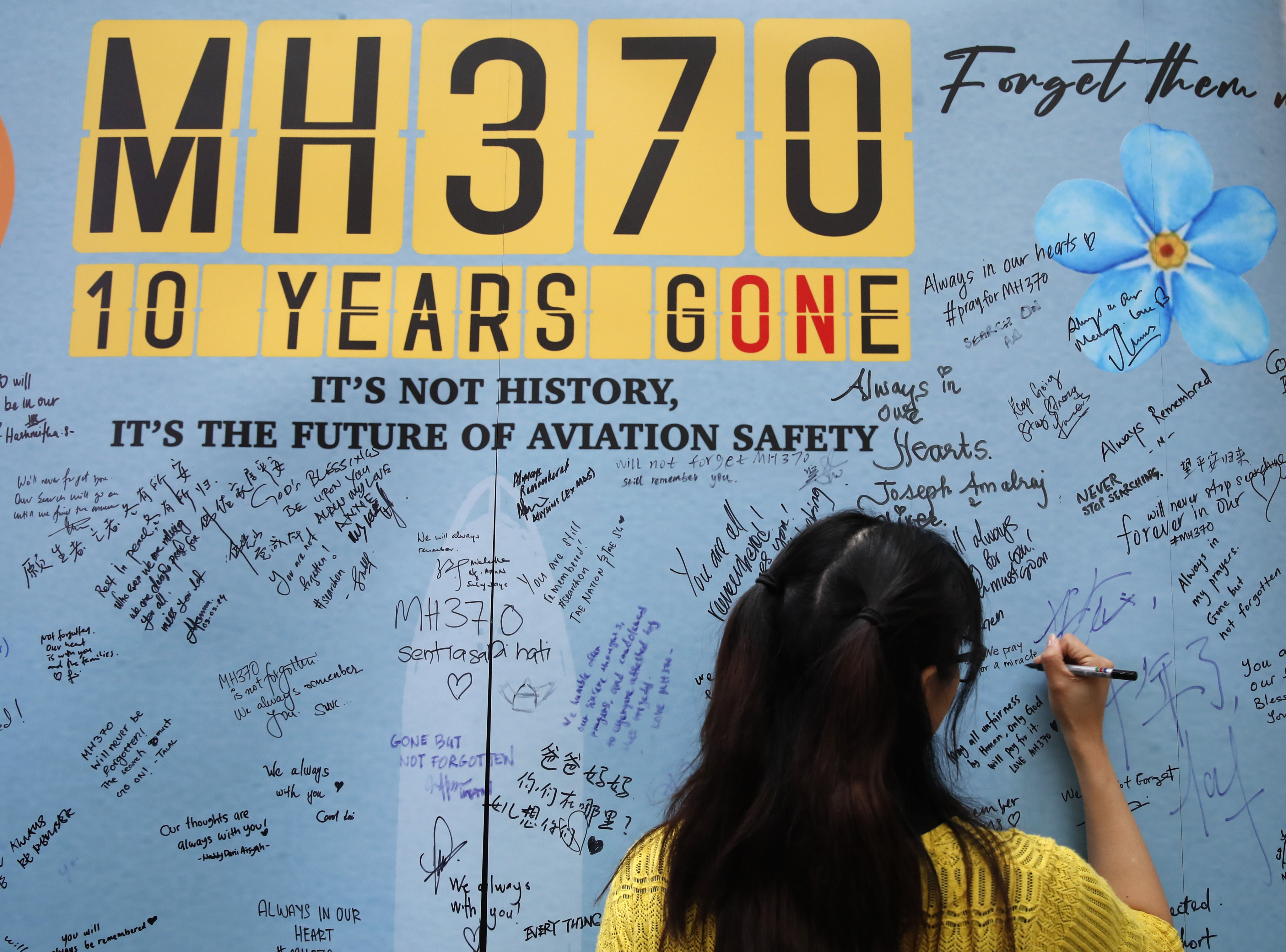 A woman writes on the message board during the 10th annual remembrance event of missing flight MH 370 at a mall in Subang Jaya, Malaysia on March 3, 2024. Photo: AP
