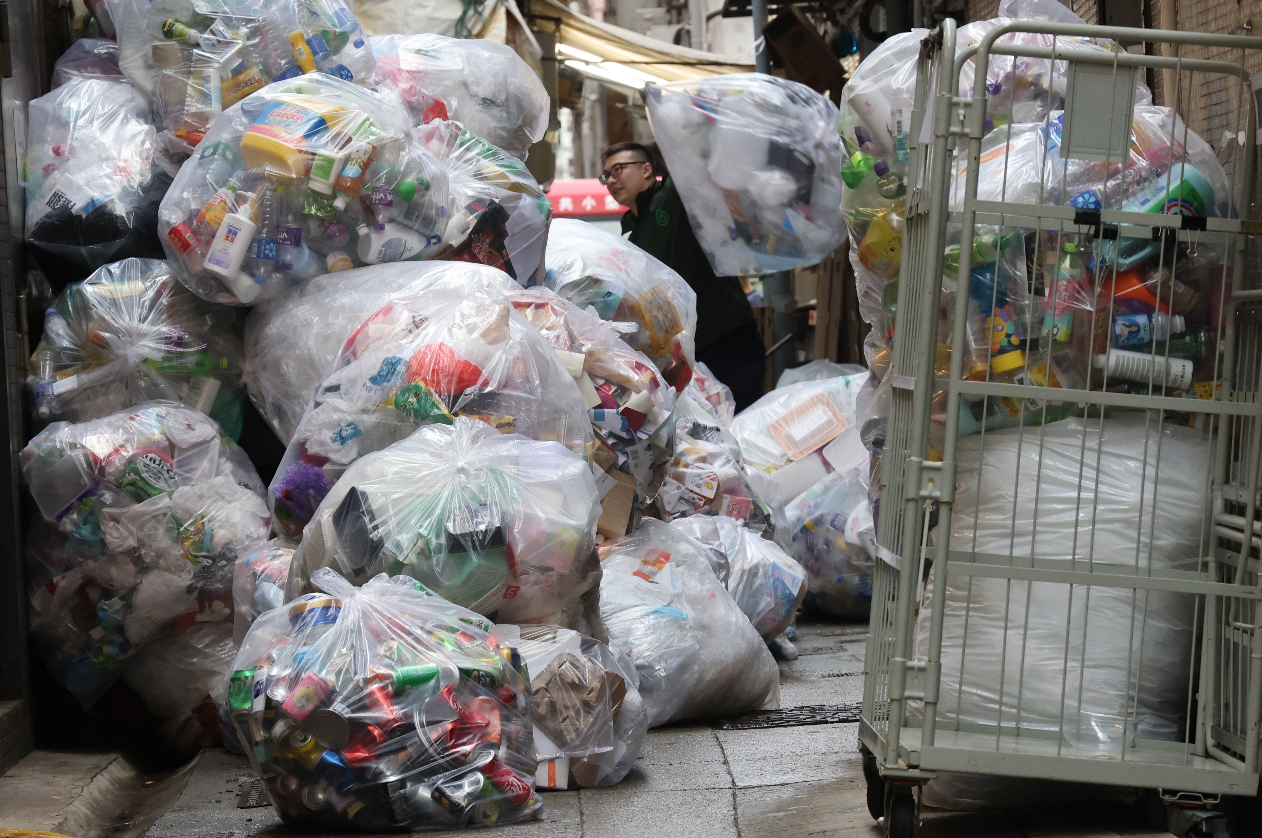 A worker at the Green Hung Hom Recycling Store clears waste piled up in front of a Green@Community recycling centre on February 7. The absence of recycling bins in many parts of Hong Kong is hampering efforts to prepare the public for the upcoming waste charging scheme. Photo: Jelly Tse