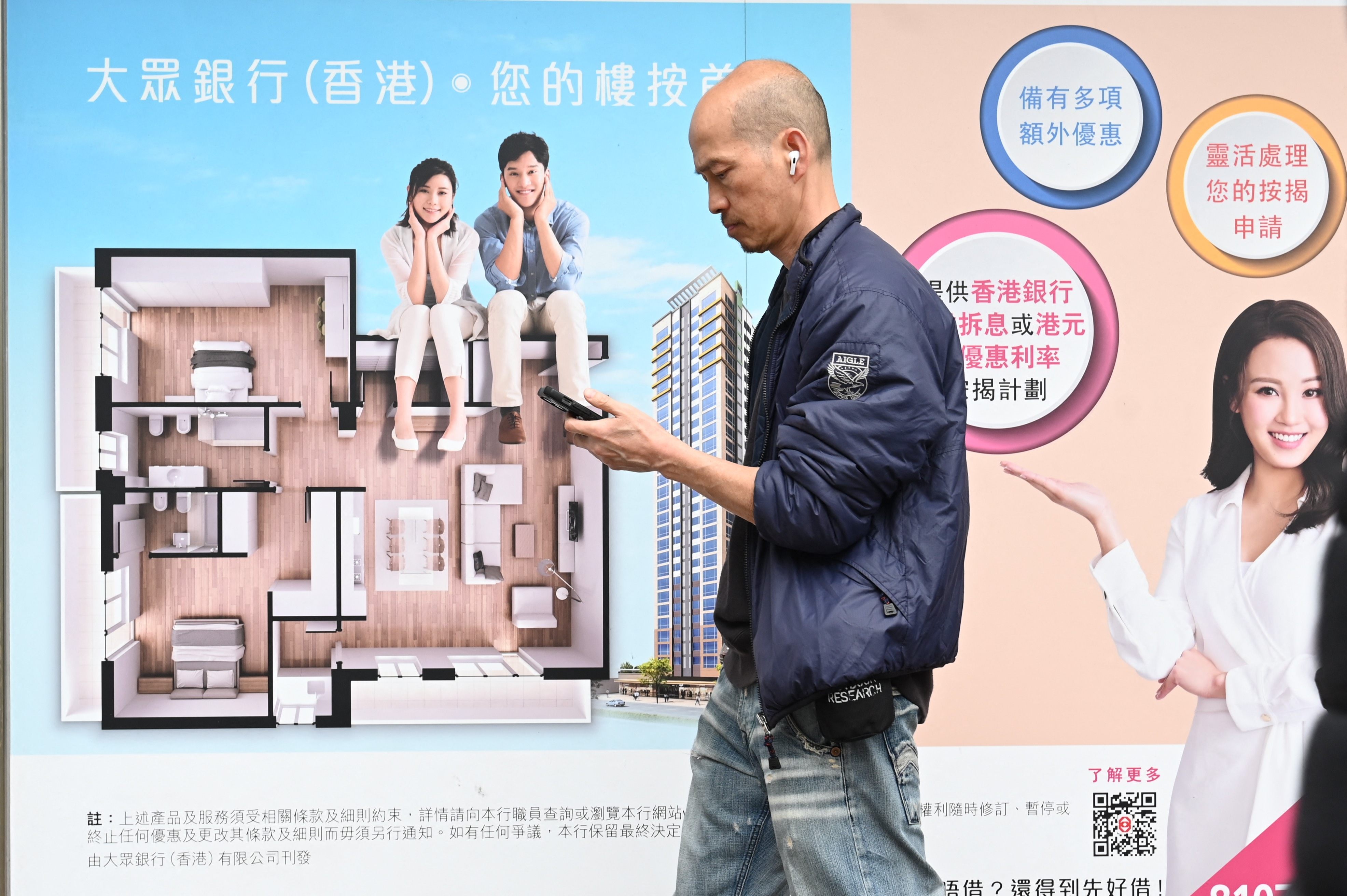 A man uses his photo outside a bank advertising mortgages in Hong Kong on February 28. Hong Kong has dropped all property market curbs in a bid to boost buyer sentiment. Photo: AFP