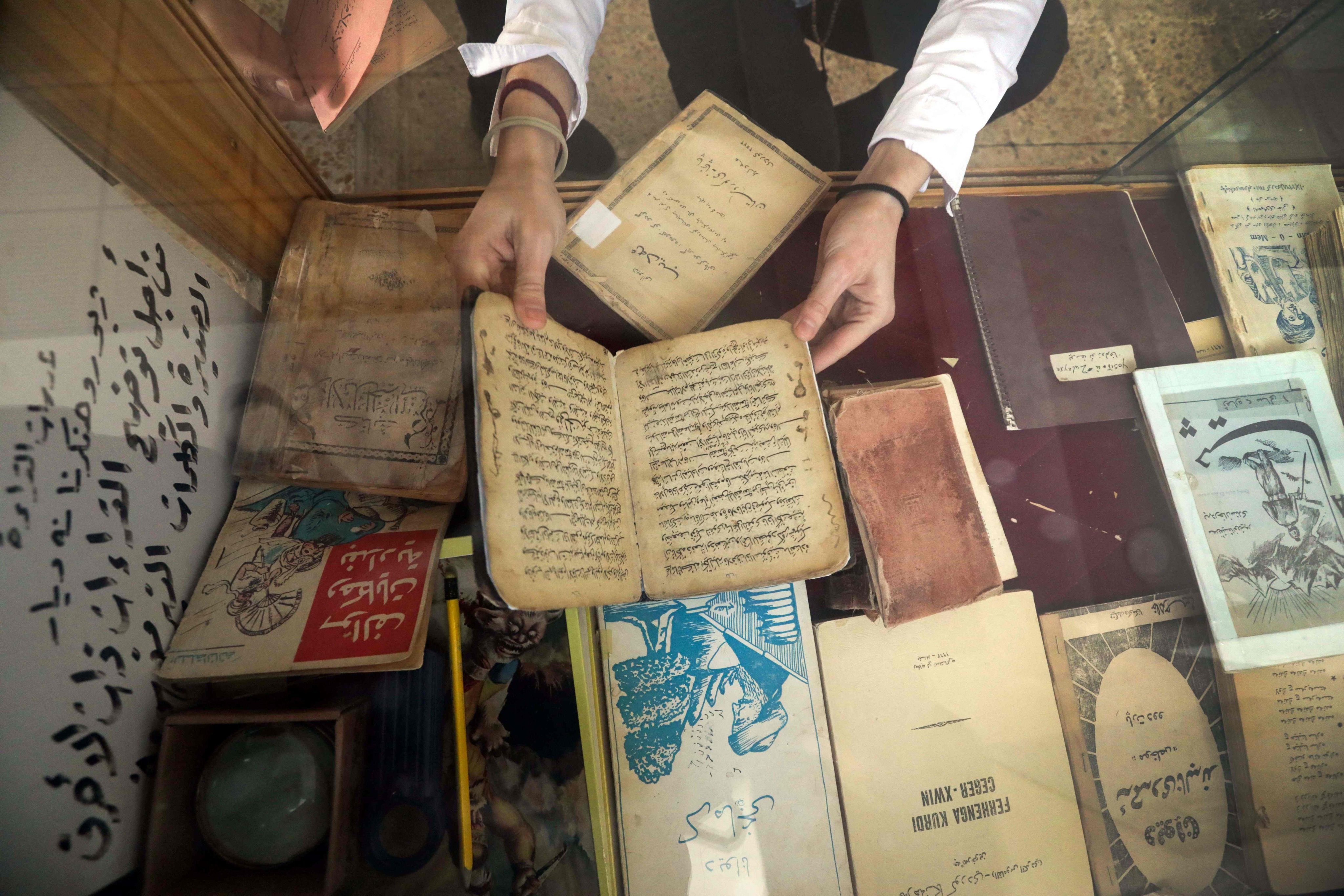 A member of the Kurdistan Centre for Arts and Culture inspects old books before making digital copies, in the Iraqi city of Dohuk. Photo: AFP 
