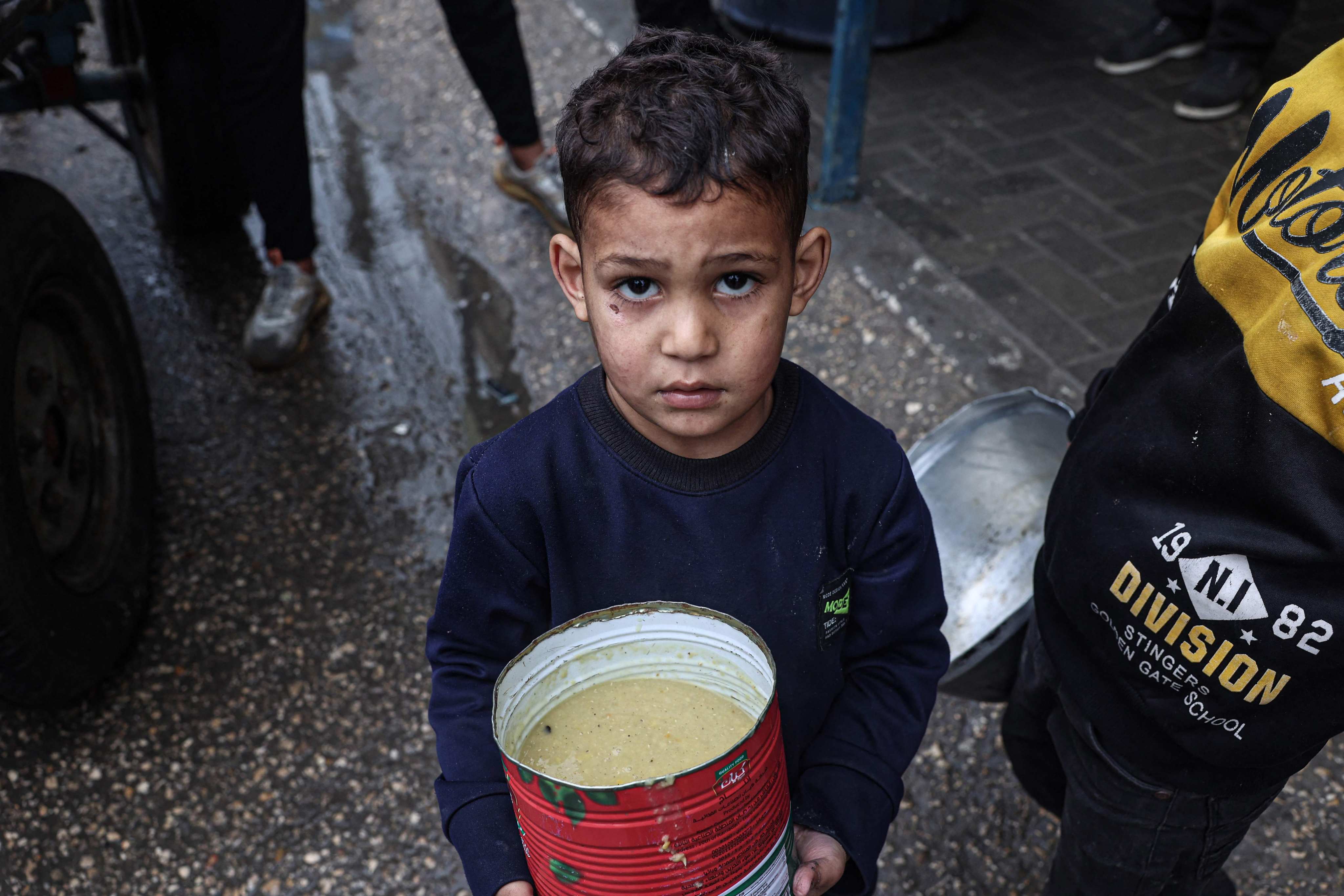 A displaced Palestinian child carries a ration of red lentil soup, distributed by volunteers in Rafah in the southern Gaza Strip on February 18. Photo: AFP