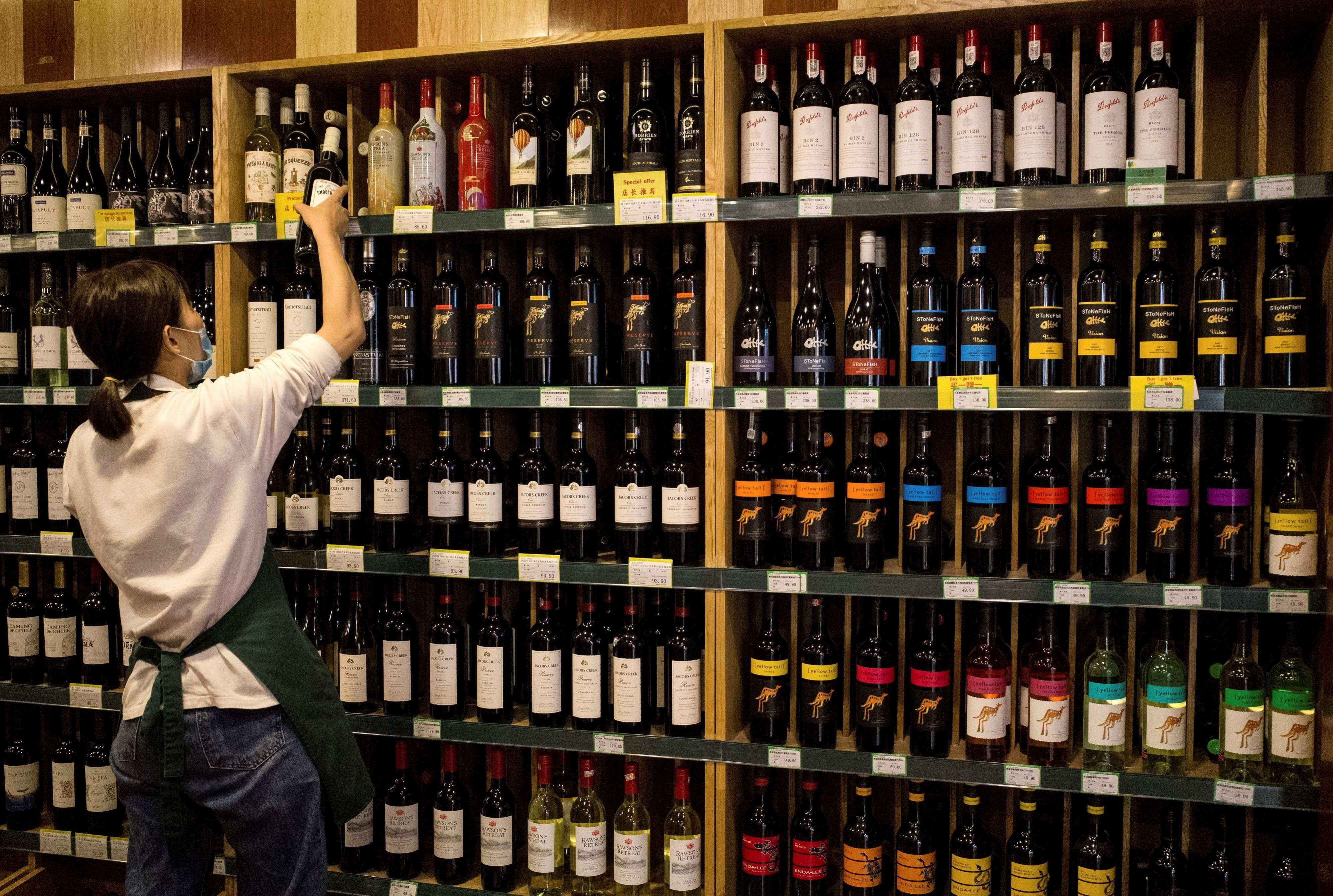 An employee placing a bottle of wine next to Australian made wine at a store in Beijing. China is set to end punitive tariffs on Australian wine in the coming weeks. Photo: AP
