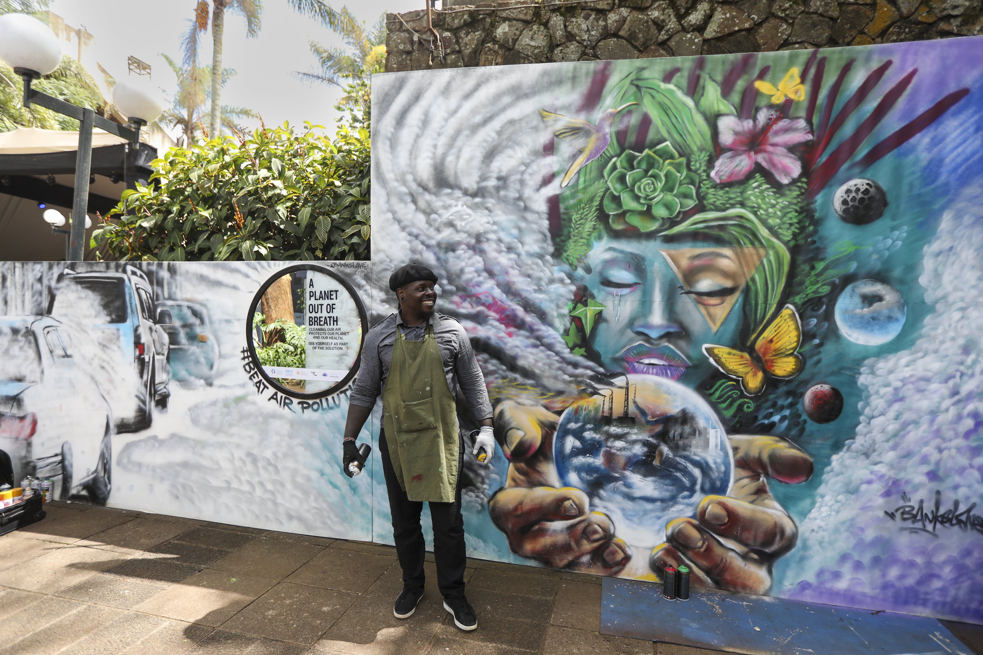 Kenyan graffiti artist Kevin Agwona, popularly known as “Bankslave”, stands in front of his mural advocating for clean air, during the sixth UN Environment Assembly, in Nairobi, Kenya, on February 29. Photo: EPA-EFE