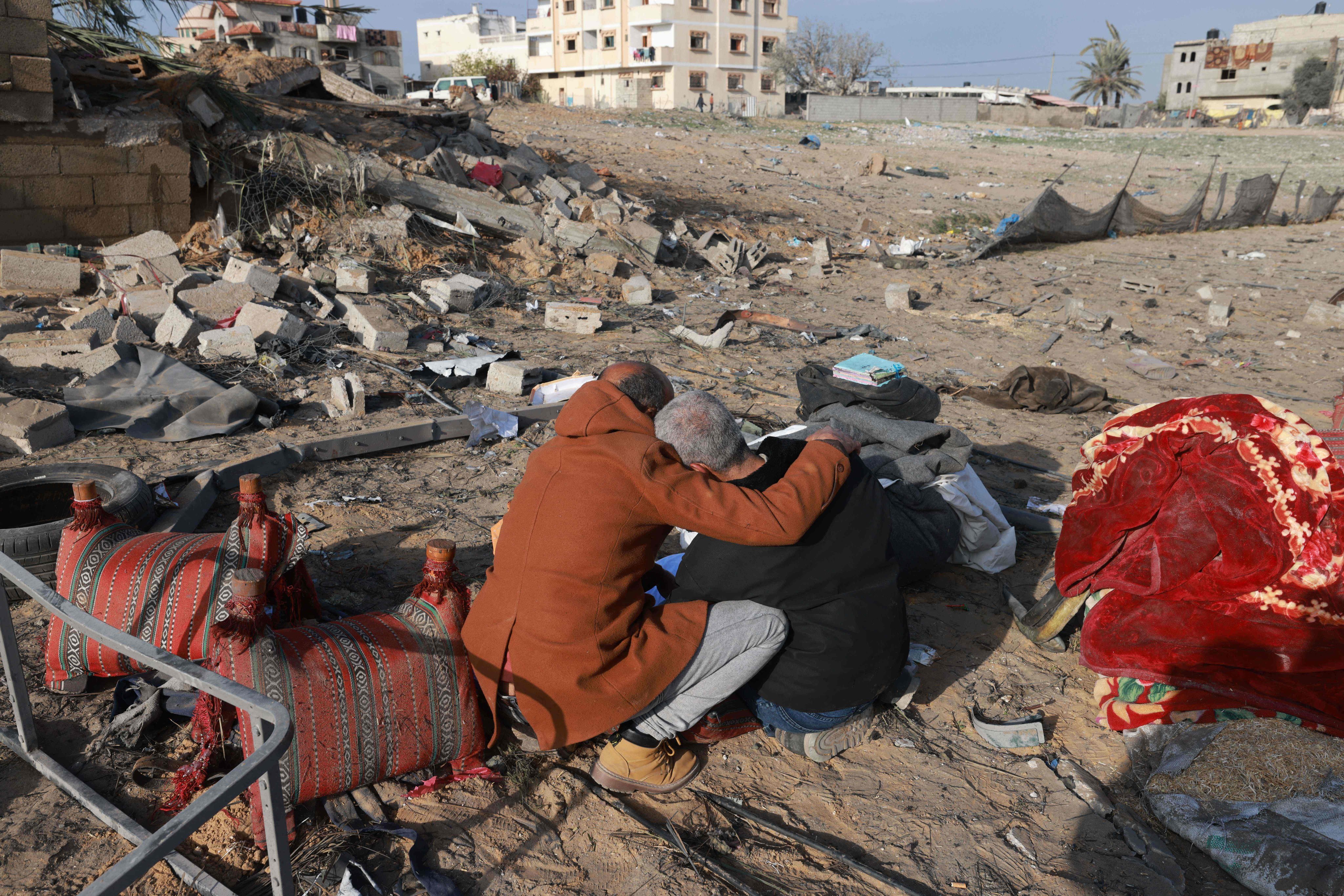 A Palestinian man comforts another as they inspect the destruction in Rafah. Photo: AFP