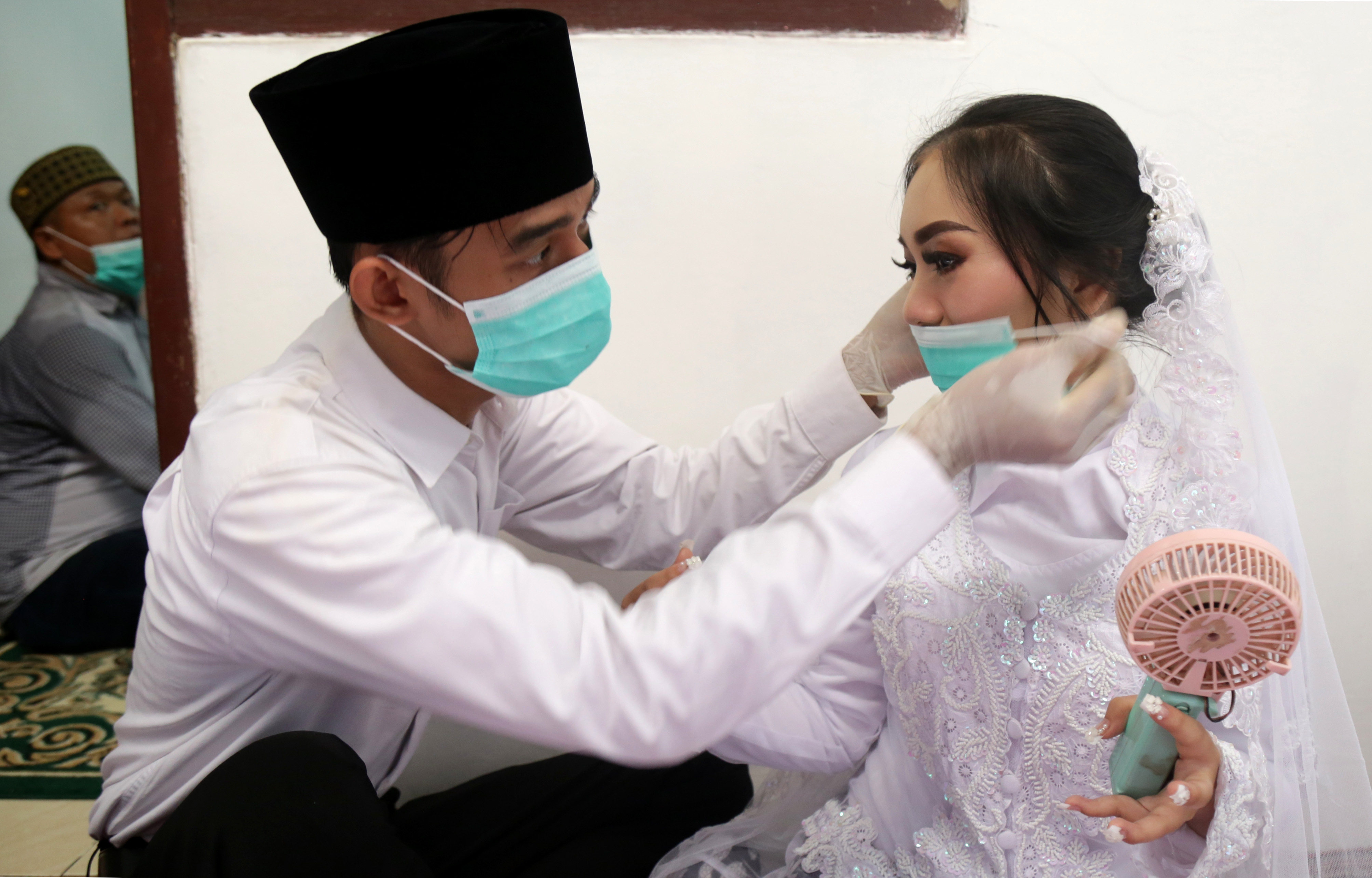 A groom puts a face mask on his bride before their wedding ceremony in Jakarta. Indonesia recorded only 1.79 million marriages in 2020. Photo: AFP 