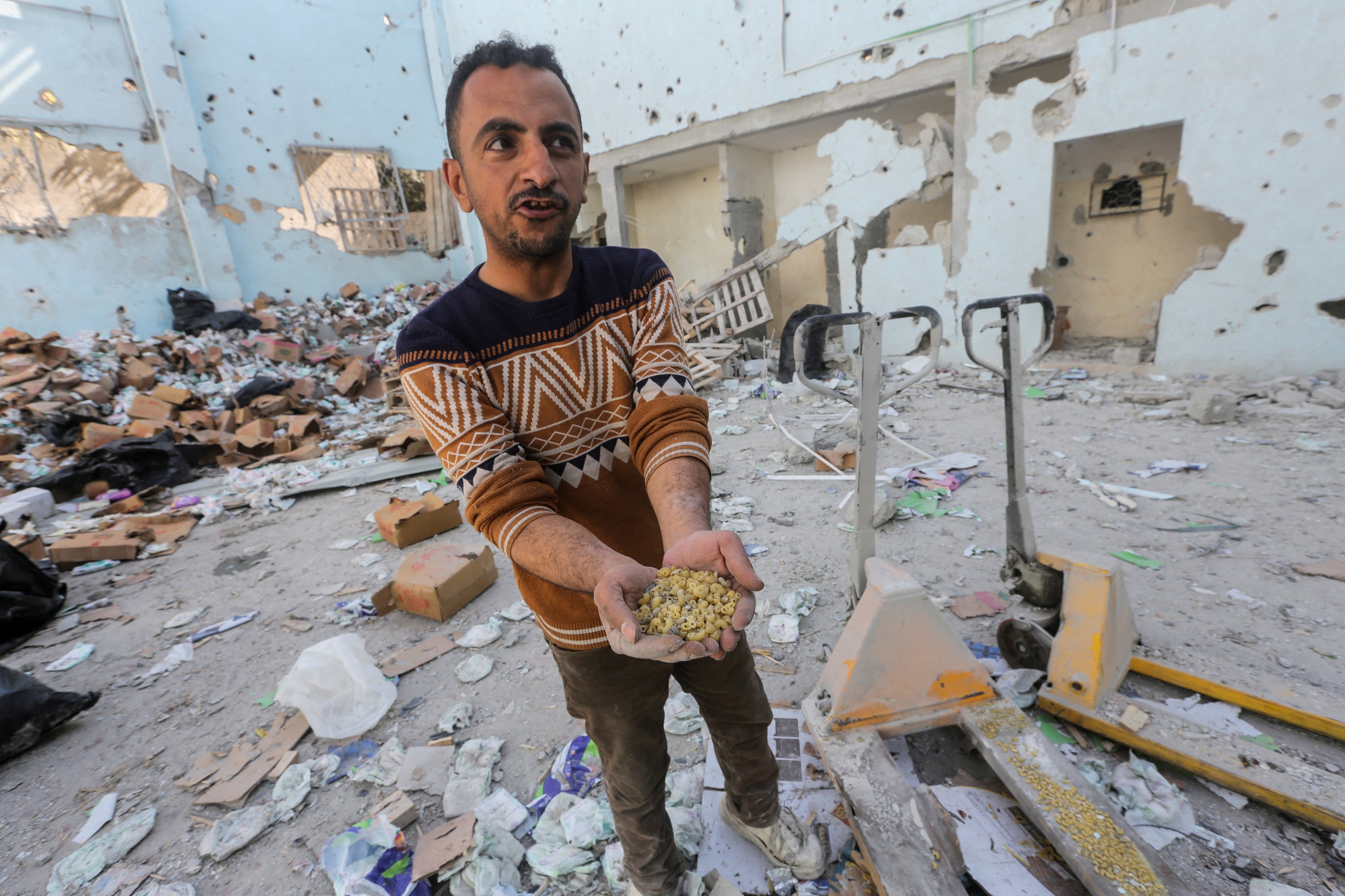 A Palestinian holds uncooked pasta  in his hands at the site of an Israeli strike on an aid warehouse in the central Gaza Strip on Thursday. Photo: Reuters 