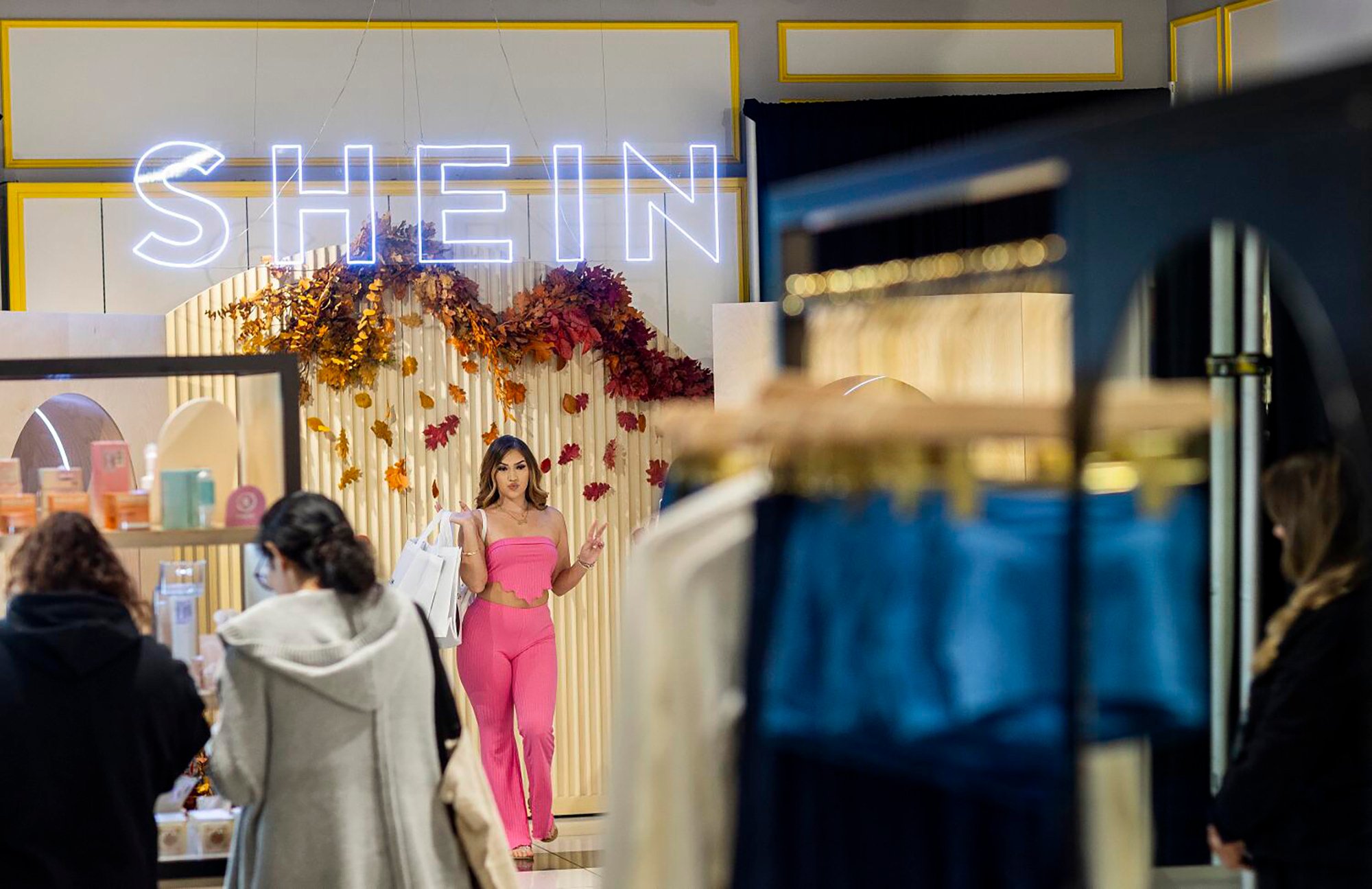 A woman poses for photos with her purchases after being among the first group of shoppers at a Shein pop-up in Ontario, California, in October 2023. Photo: TNS