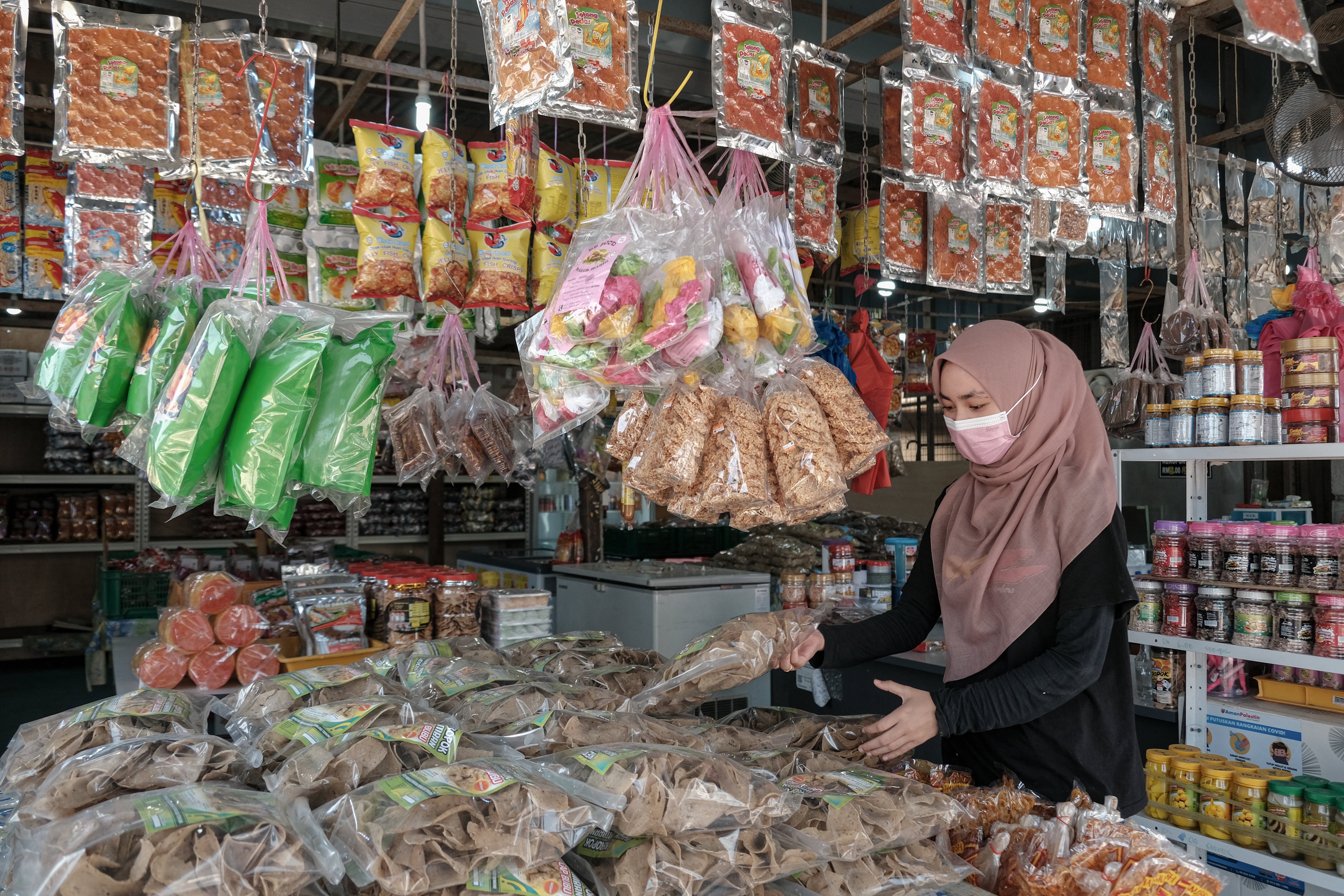 A worker arranges packaged fish crackers at a store in Terengganu. Ordinary Malaysians have been hit by the ringgit’s drop in value, as the cost of shopping surges with each depreciation. Photo: Bloomberg