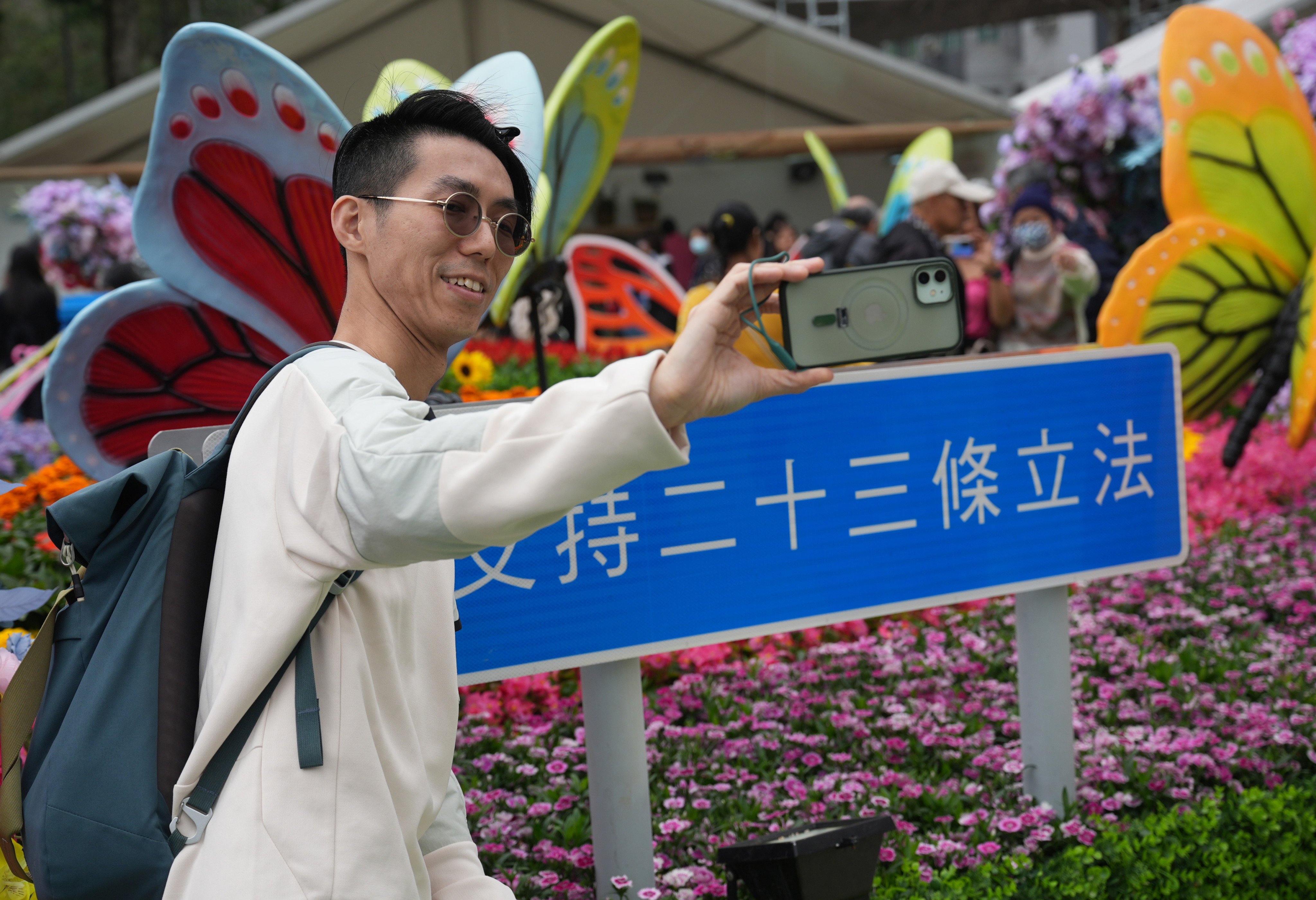 Visitors take selfies in front of a sign supporting the legislation of article 23. Photo: Eugene Lee