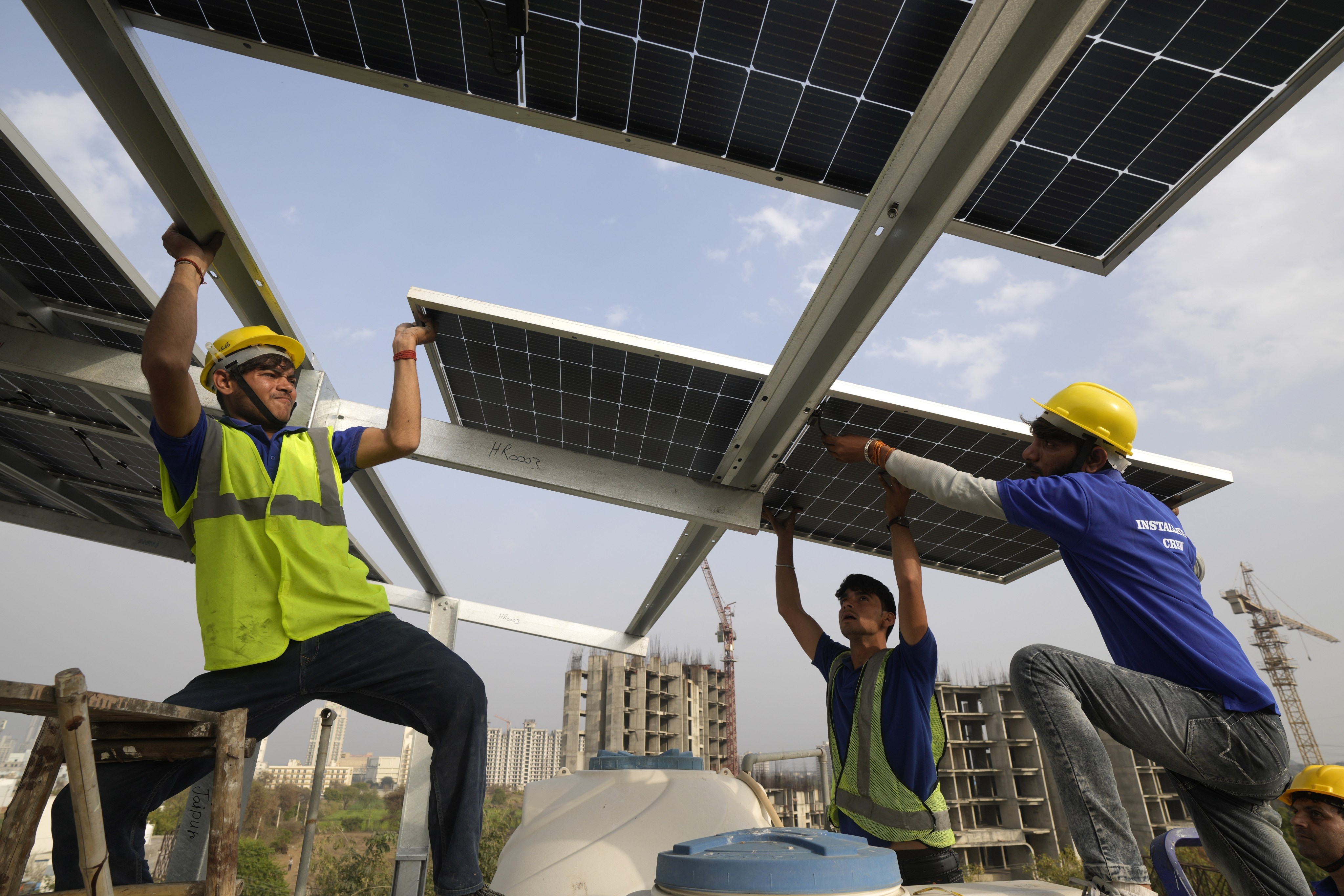Workers put up a solar panel on the rooftop on the outskirts of New Delhi, India on February 20. Photo: AP