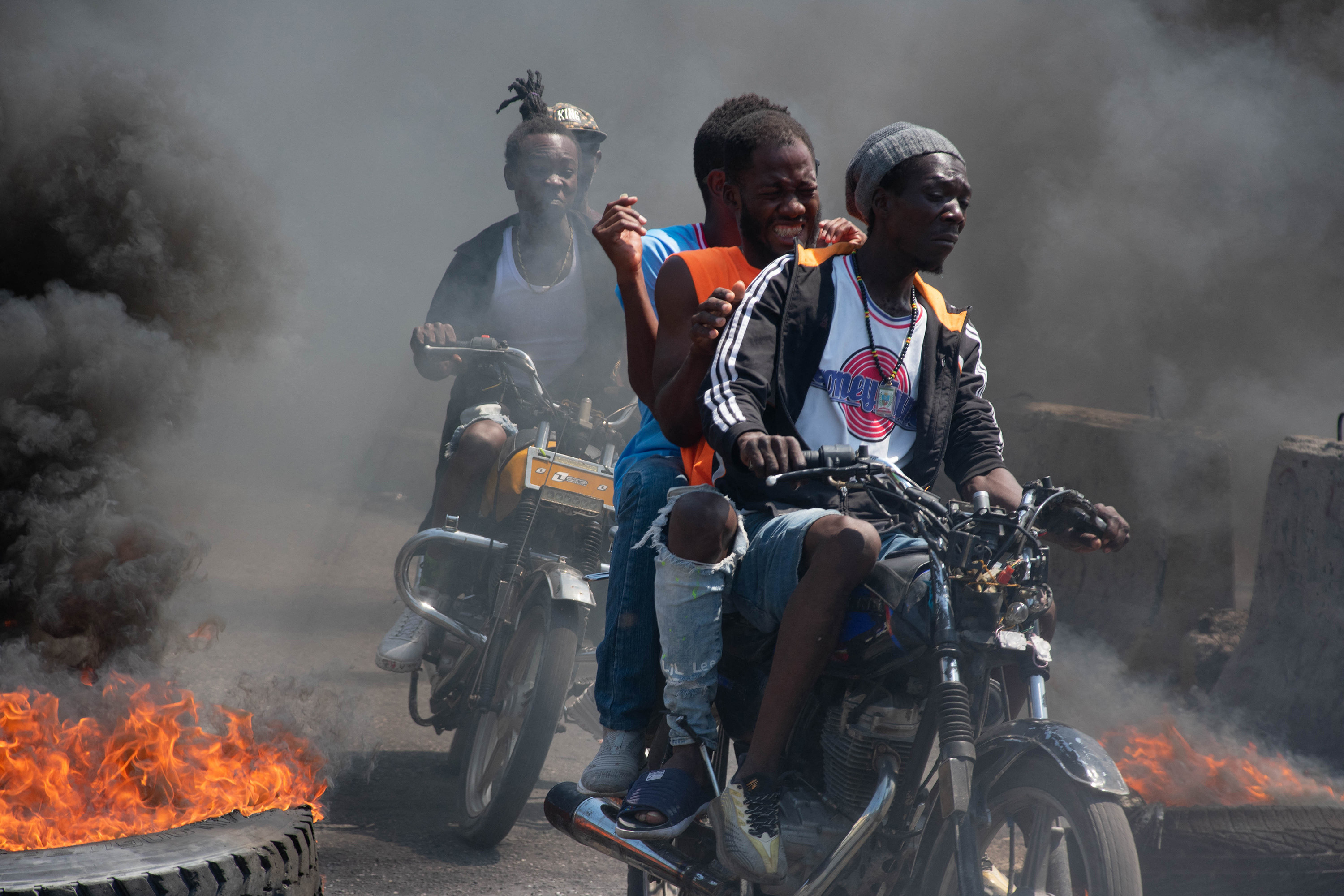 Men on motorcycles drive past burning tyres in Port-au-Prince, Haiti. Photo: TNS