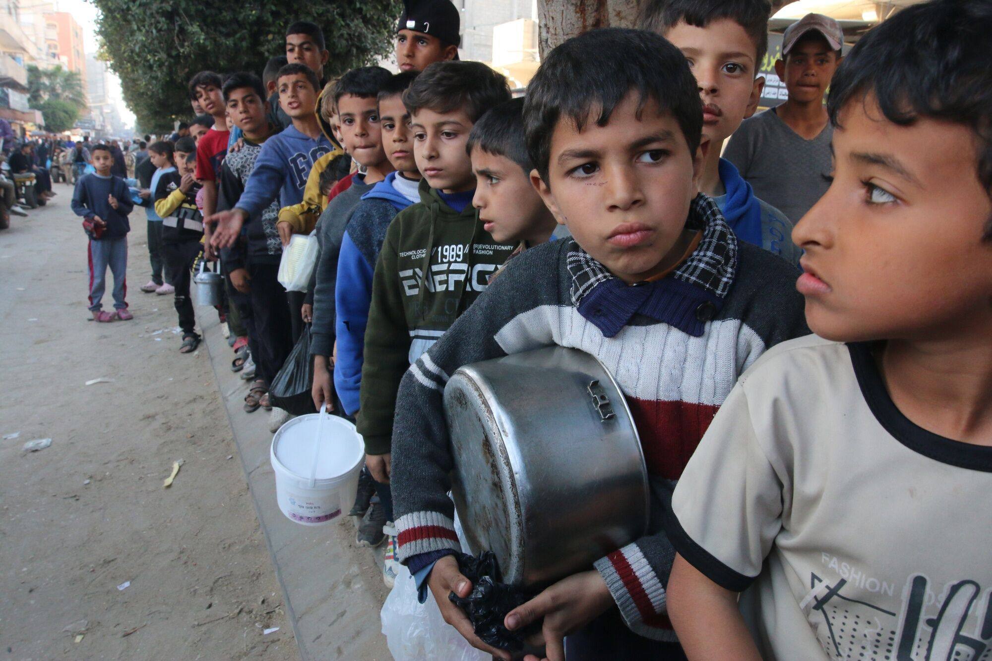 Displaced Palestinian children queue to collect free food handouts from a street kitchen in central Gaza on Wednesday. Photo: Bloomberg