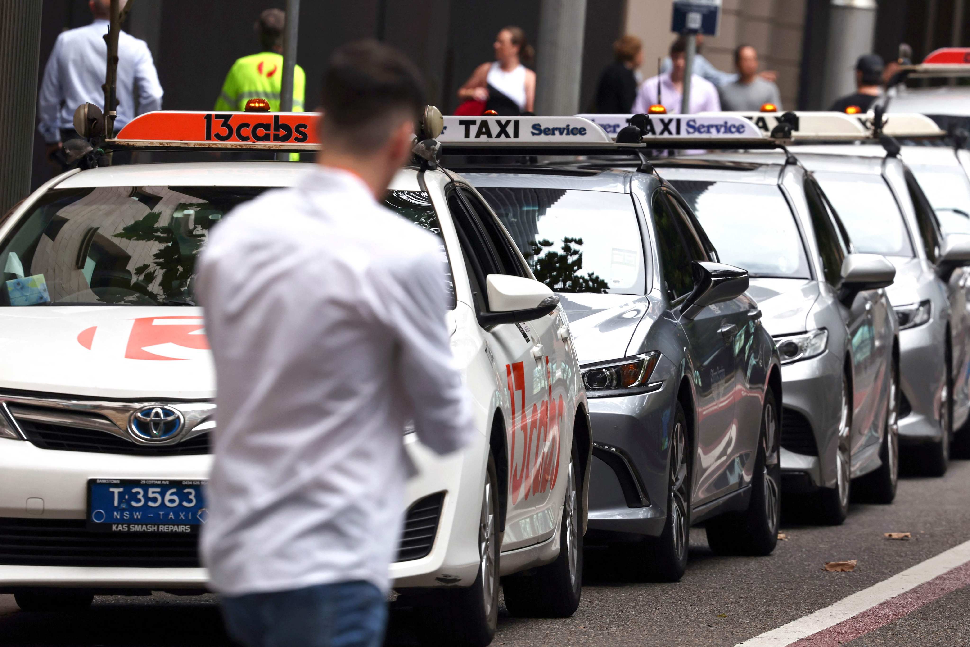 A pedestrian walks past a row of taxis in central Sydney on Monday. Uber entered Australia in 2012. Photo: AFP