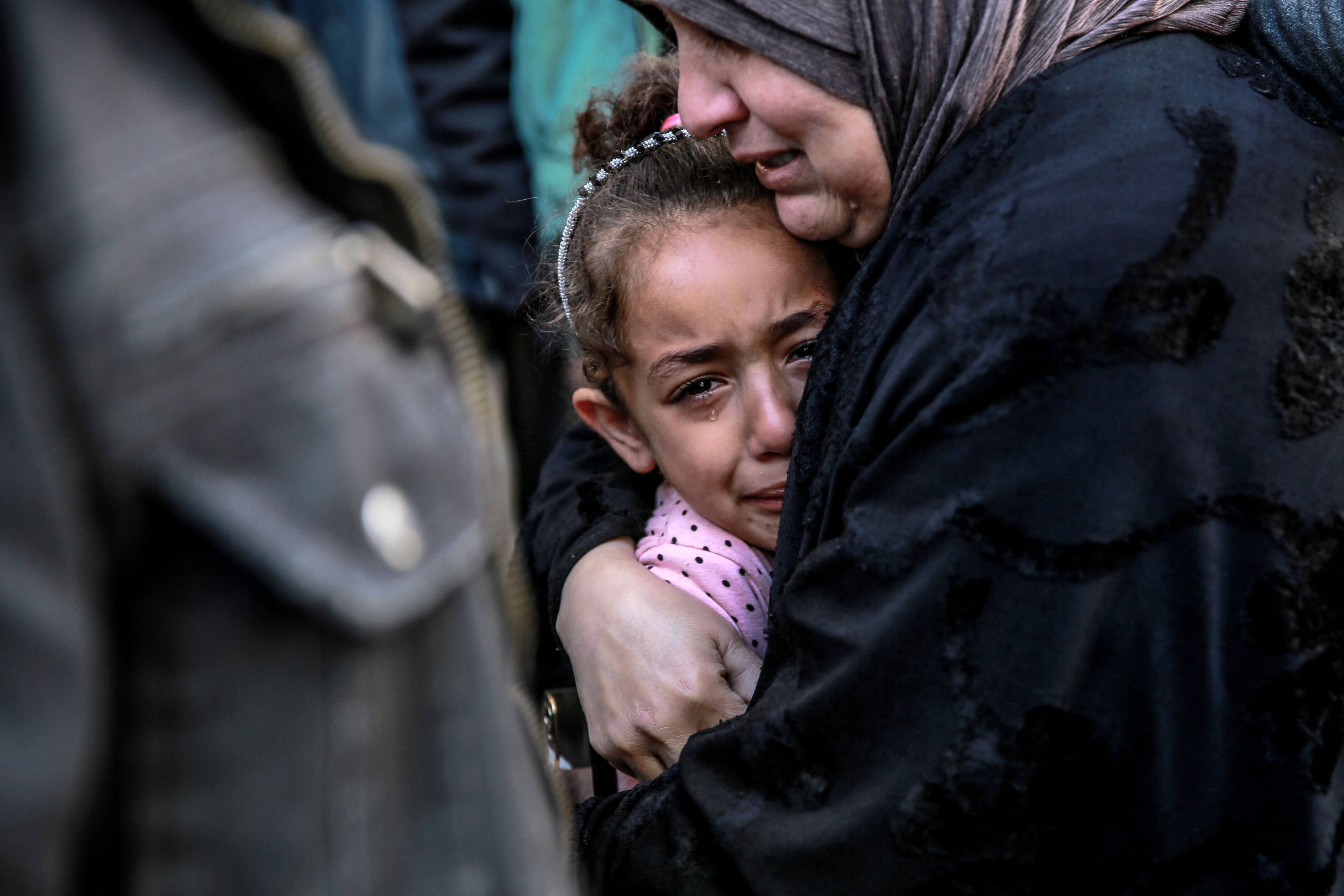 A Palestinian woman holds a child in front of the morgue at Al-Shifa hospital in Gaza City on Friday. Photo: AFP