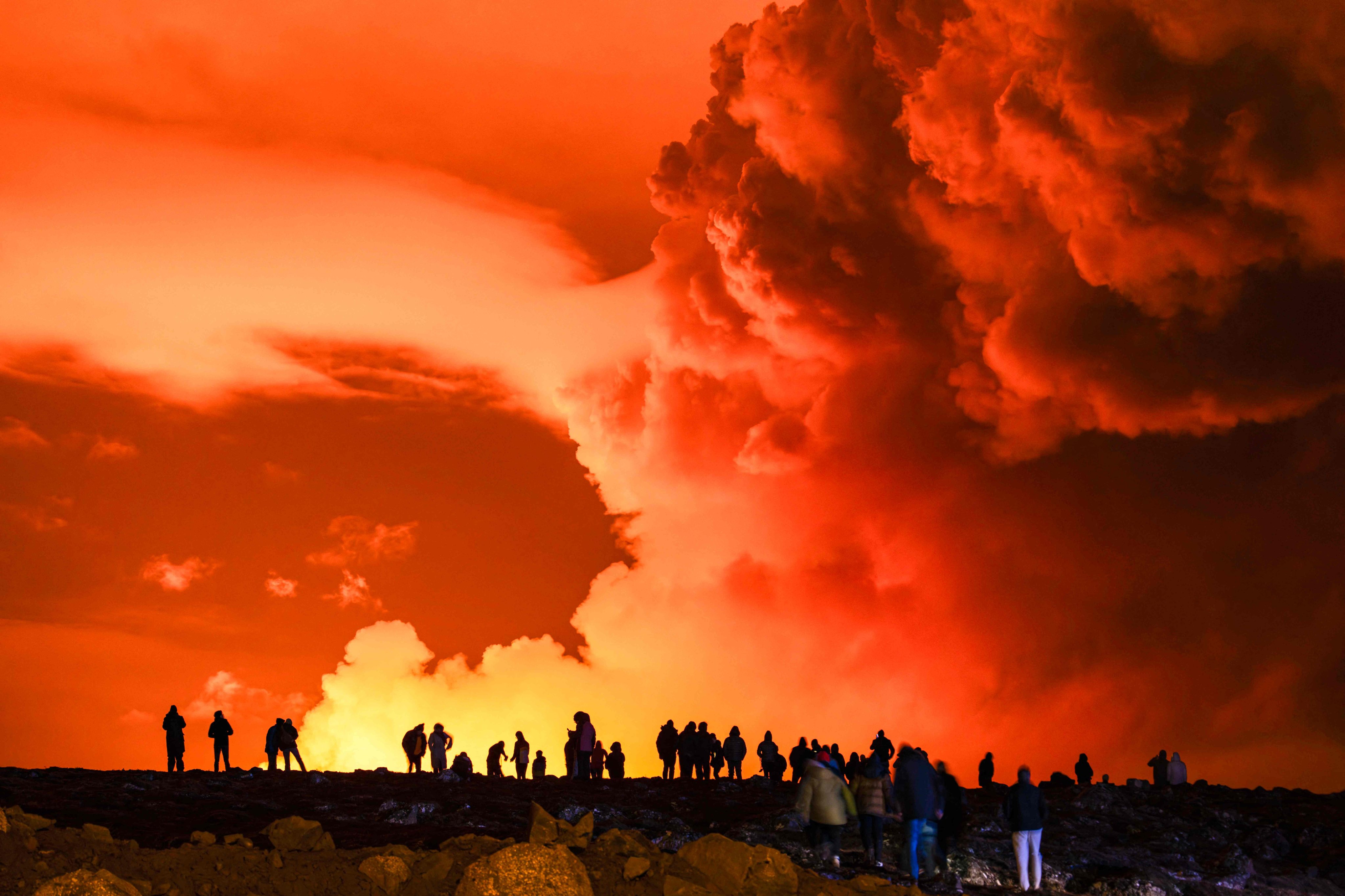 People watch as molten lava flows out from a fissure on the Reykjanes peninsula, western Iceland. Photo: AFP